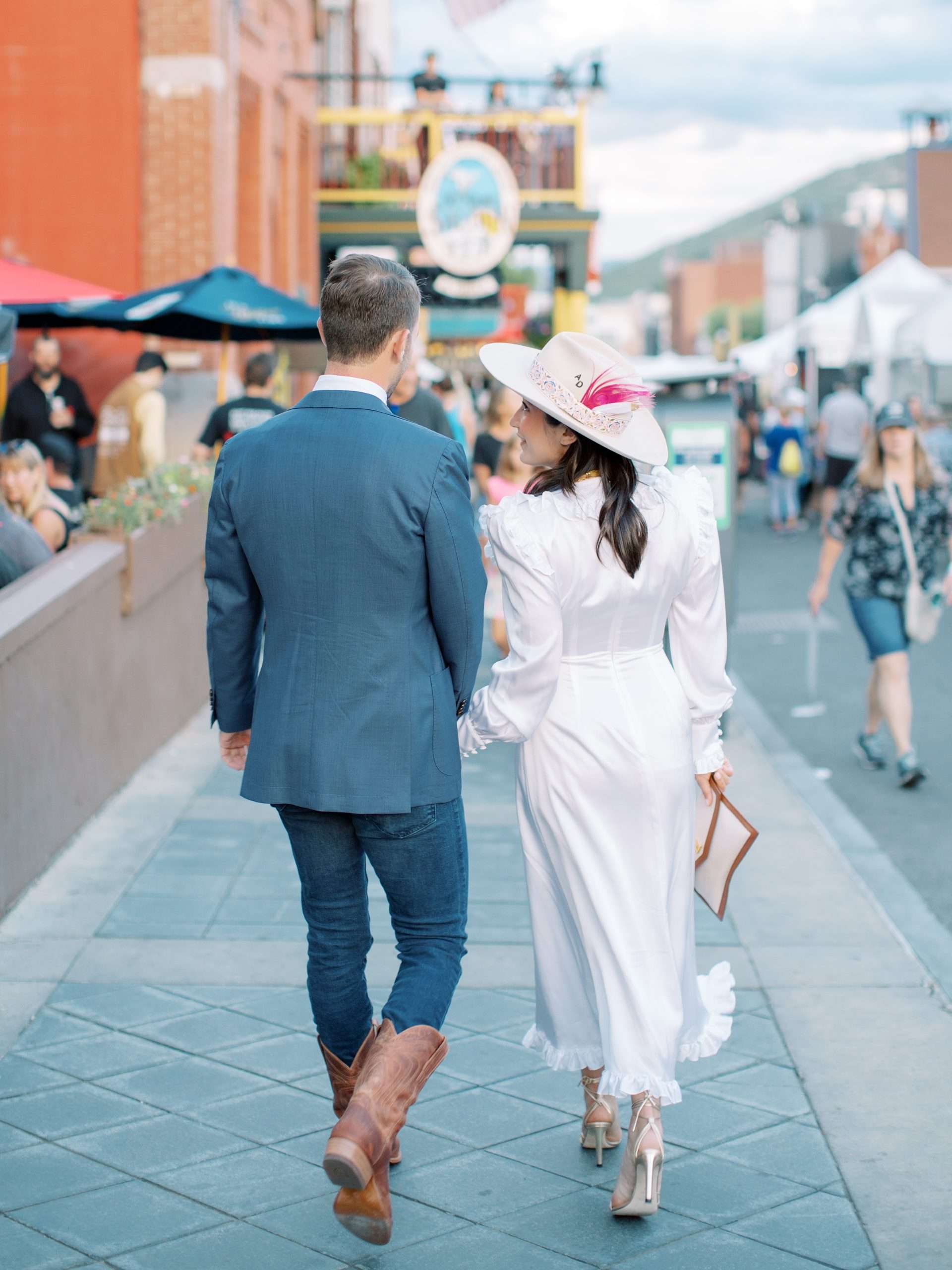 bride and groom walking down the street, bride with big hat and feather