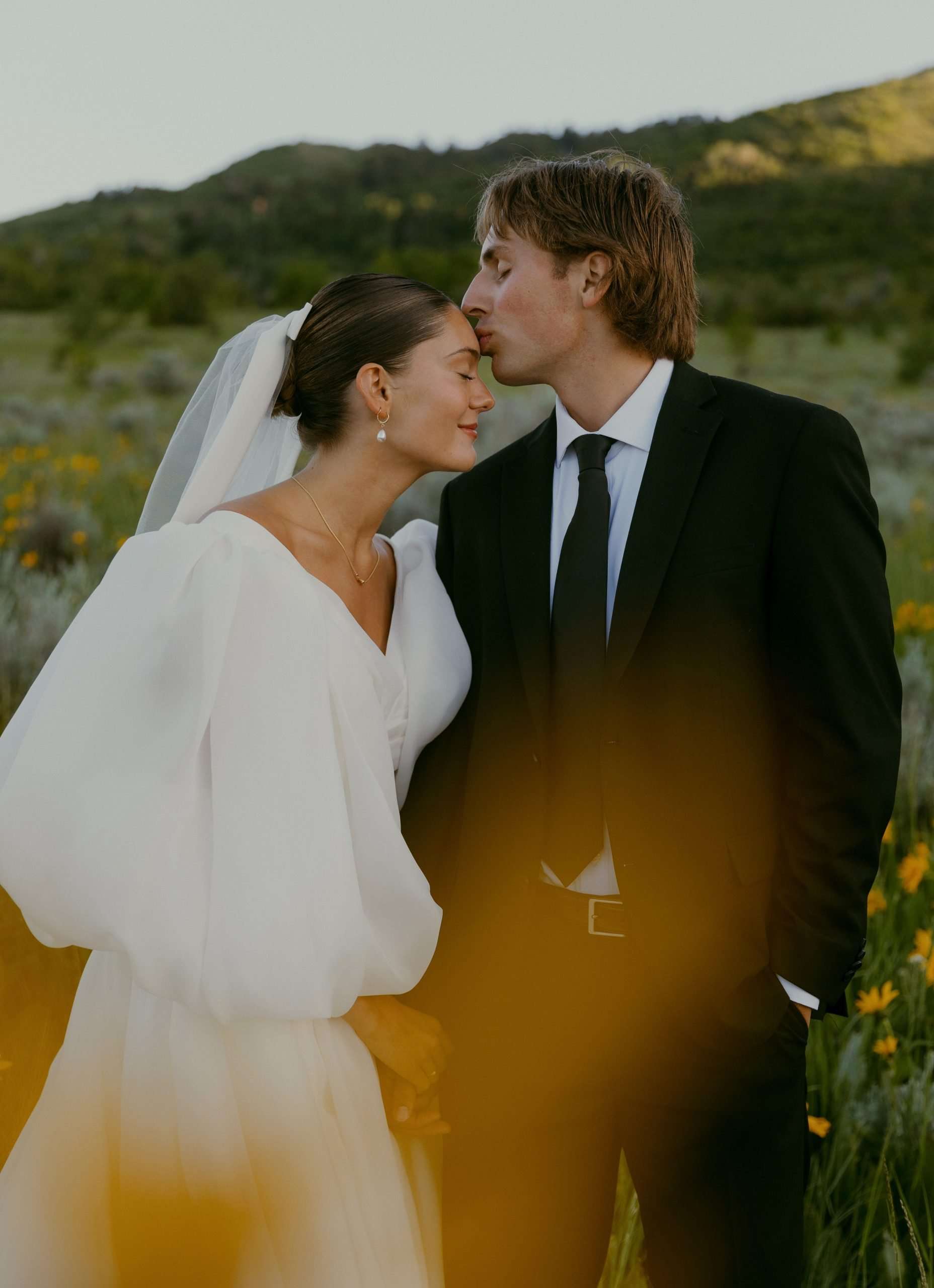 groom kissing bride's forehead in a meadow utah wedding bridal photos