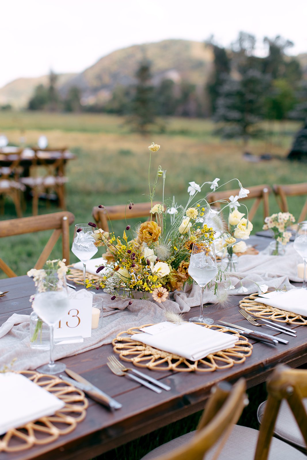 Outside reception with wooden tables with rattan chargers for a Utah Summer Wedding