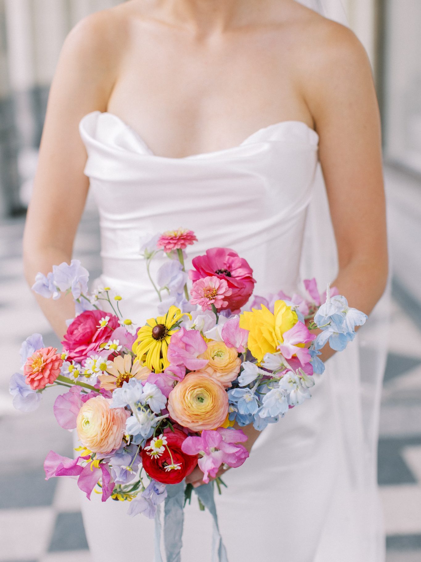 Alberta Summer Wedding bride wearing a silk strapless wedding gown and holding her vibrant bridal bouquet with pink, purple, blue, yellow, and orange organic flowers