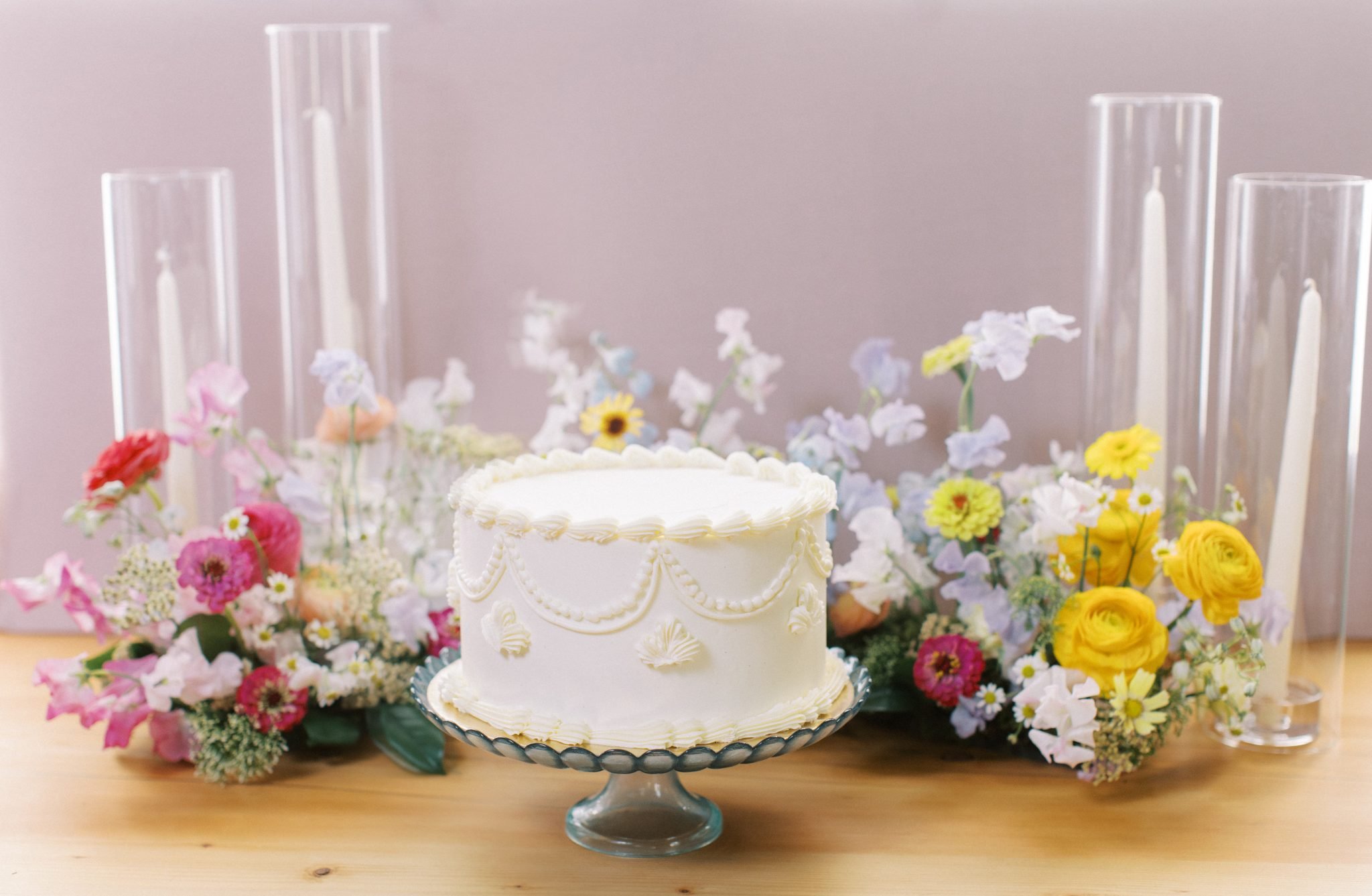 Alberta Summer Wedding on tier wedding cake with colorful florals surrounding the cake with tapered candles