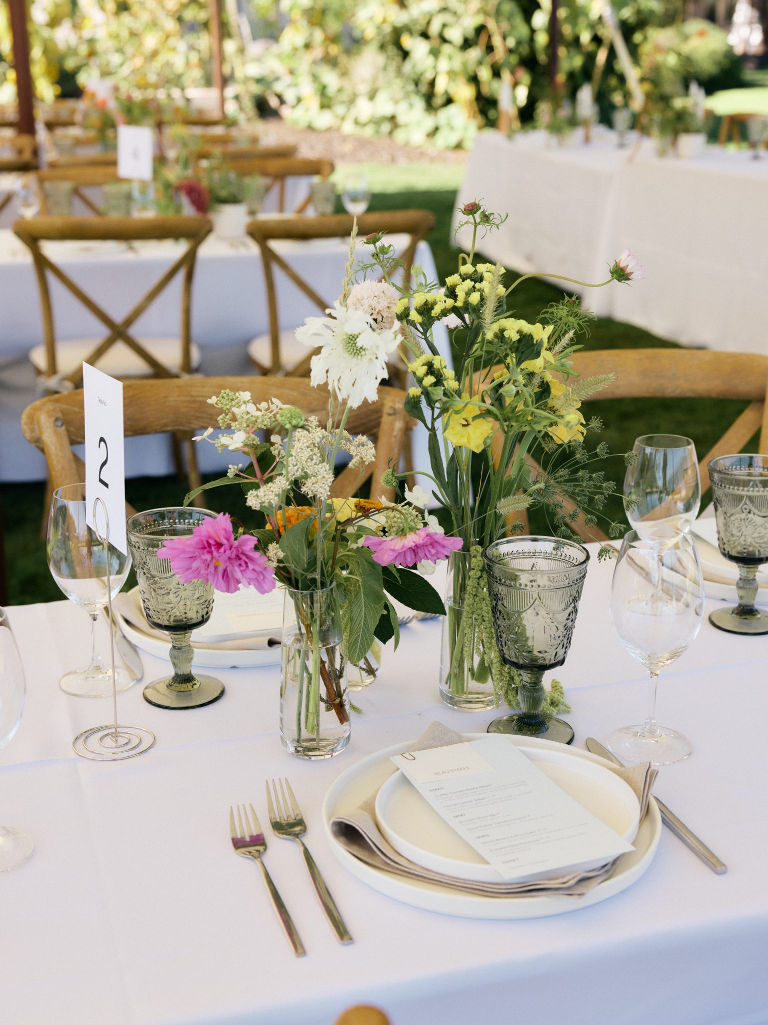 British Columbia Summer Wedding with banquet tables with vases bunched together with pink, white, and yellow florals as centerpieces