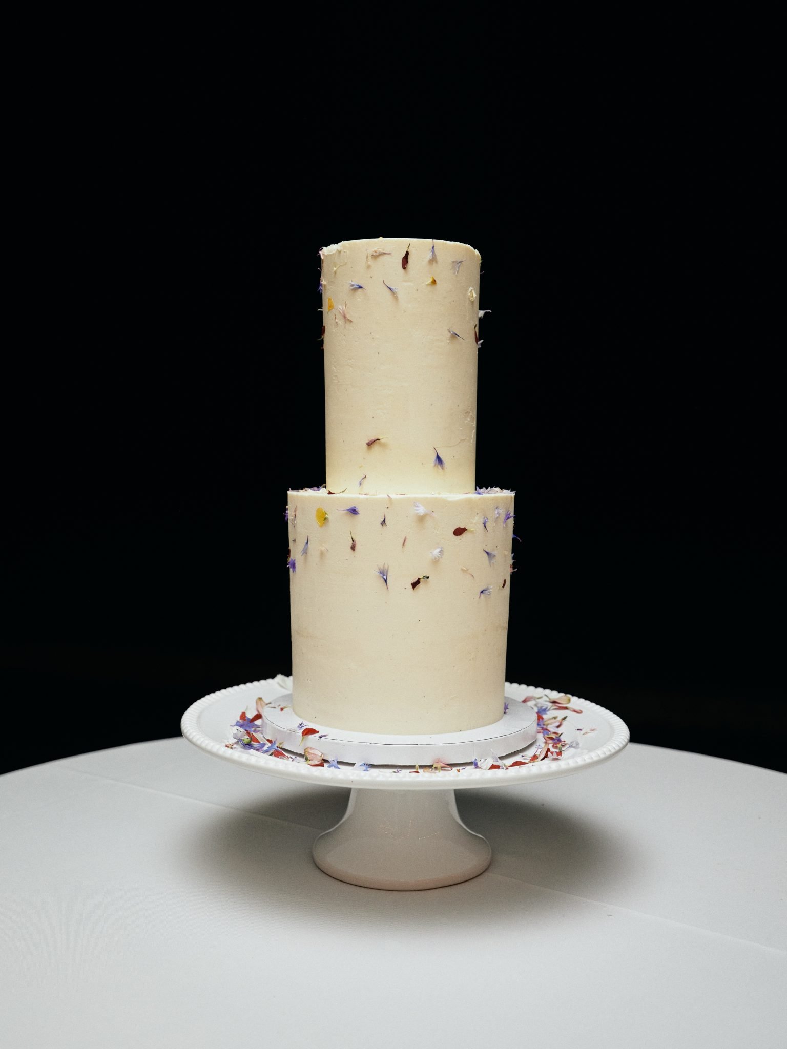 Two tiered cake with specks of flower petals for decoration for a British Columbia Summer Wedding