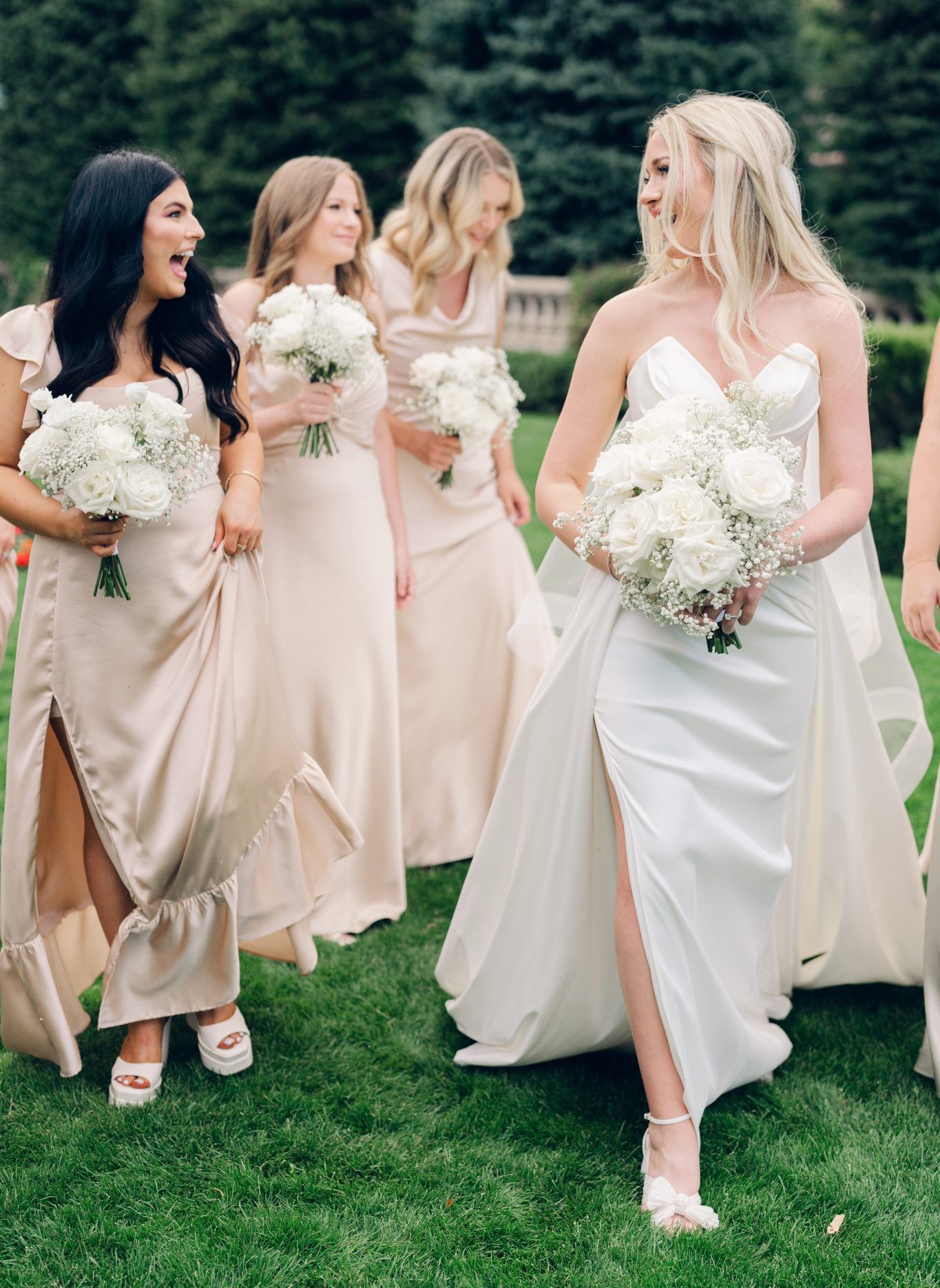 Colorado Springs Summer Wedding bridesmaids wearing champagne floor length dresses and caring white rose bouquets with baby's breath and the bride wearing her sheath wedding dress with a ballroom skirt at The Broadmoor hotel