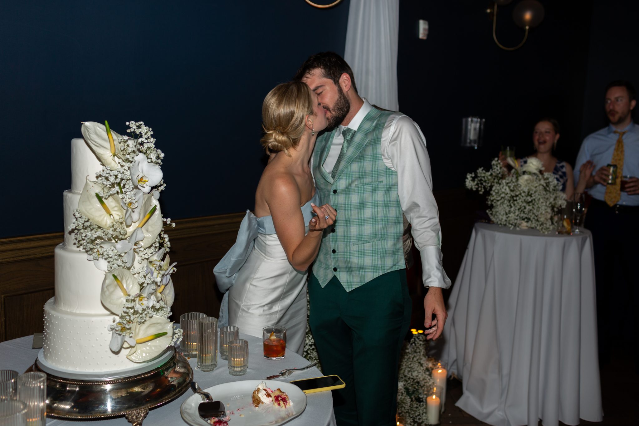 Denver Botanic Gardens Colorado Wedding couple kissing after they cut their four-tiered white cake covered in florals