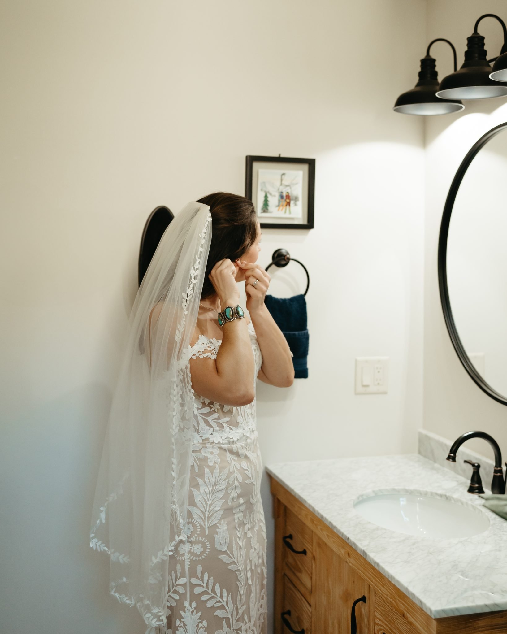Colorado Fall Wedding bride getting ready as she puts on her earrings while wearing her lace off the shoulder wedding dress