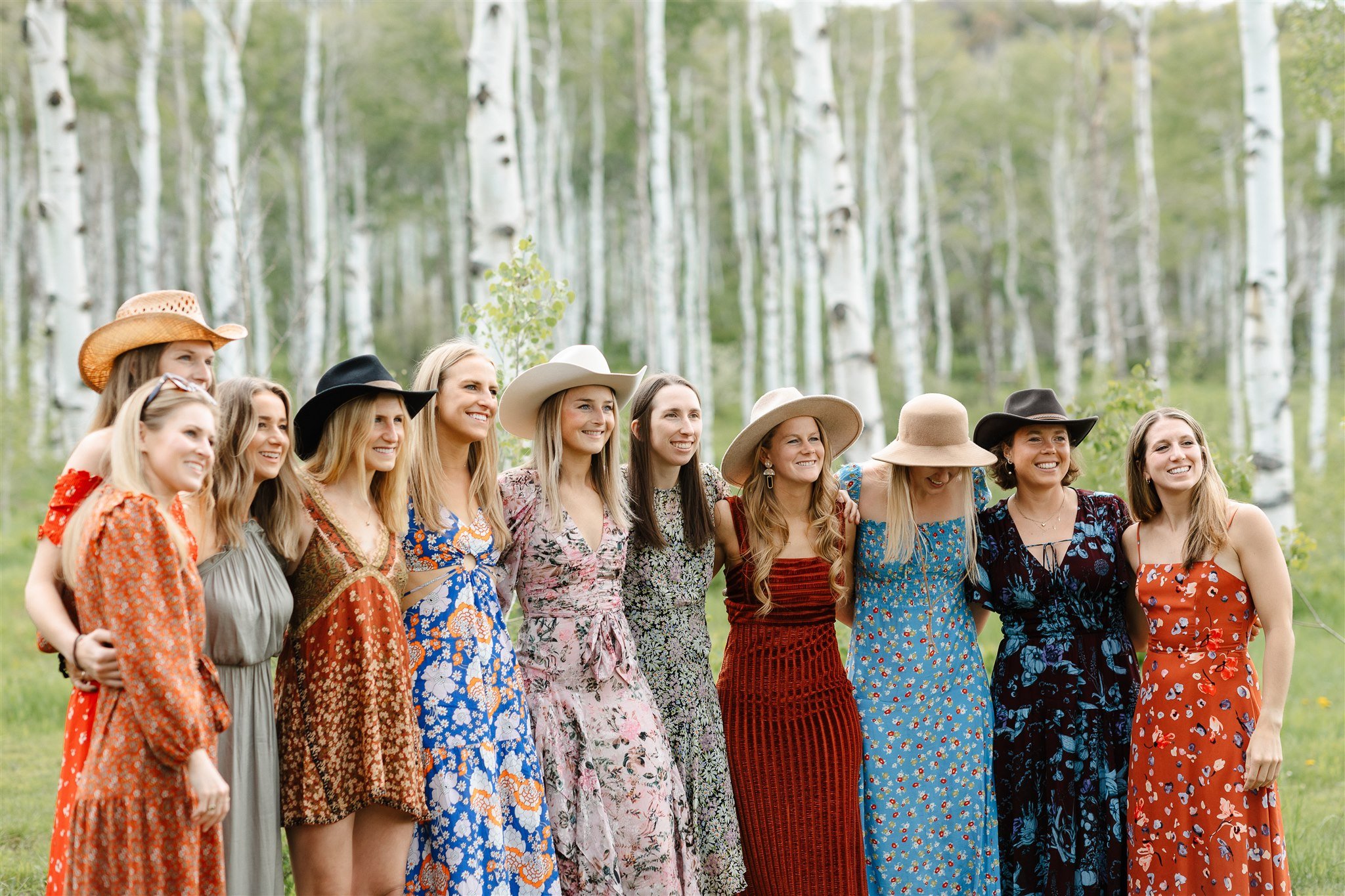 Flying Diamond Ranch Summer Wedding guests wearing colorful dresses and cowboy hats with aspen trees in the background
