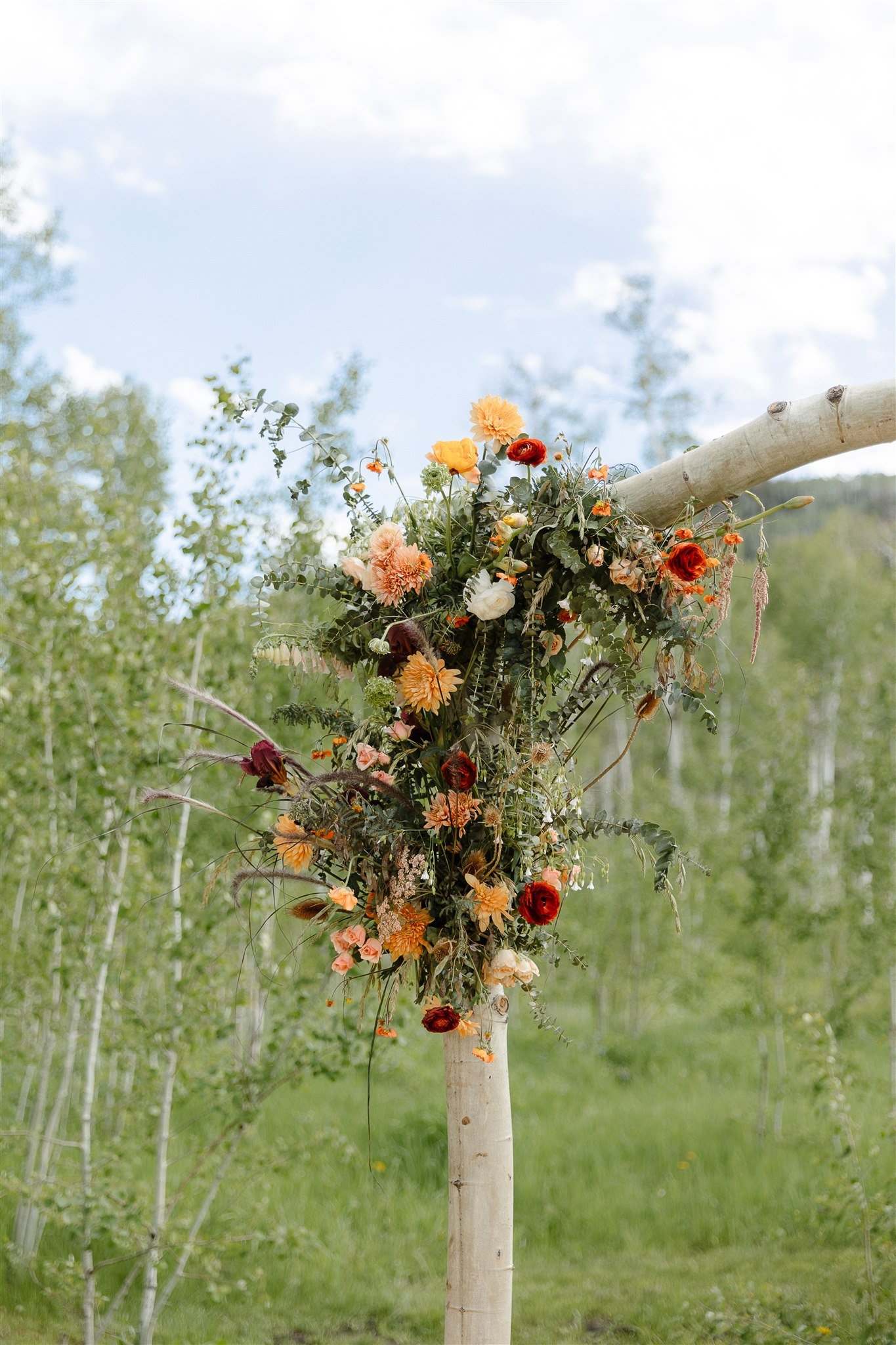 Flying Diamond Ranch Summer Wedding ceremony floral wooden altar centerpiece with orange, red, and pink hues of florals