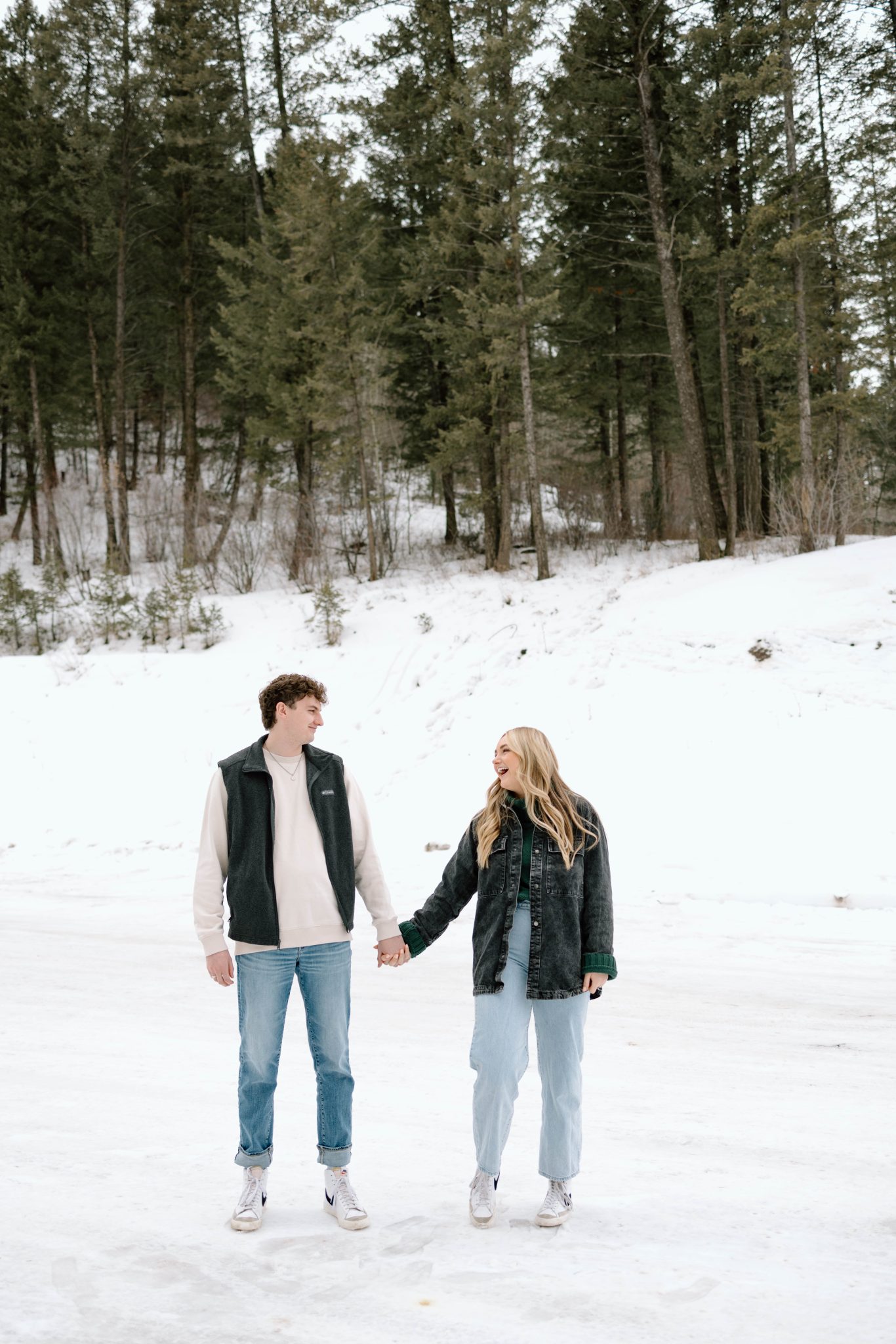 Idaho Winter Engagements holding hands in the middle of the road and looking at each other