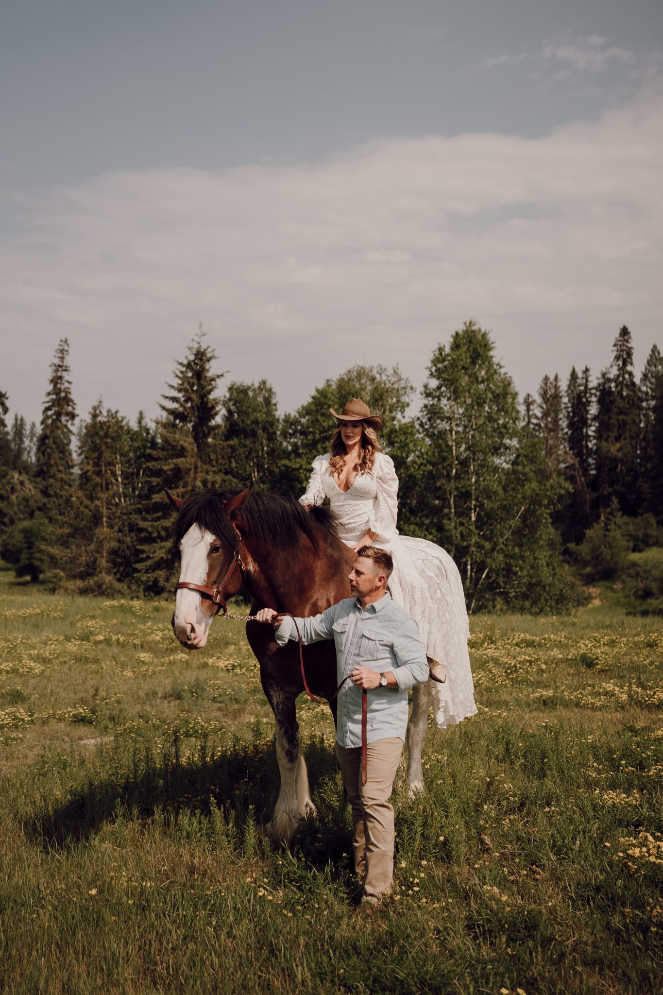 wedding morning for a Montana Summer Elopement with the bride on a horse while the groom guides the horse to walk a certain direction in a grassy field