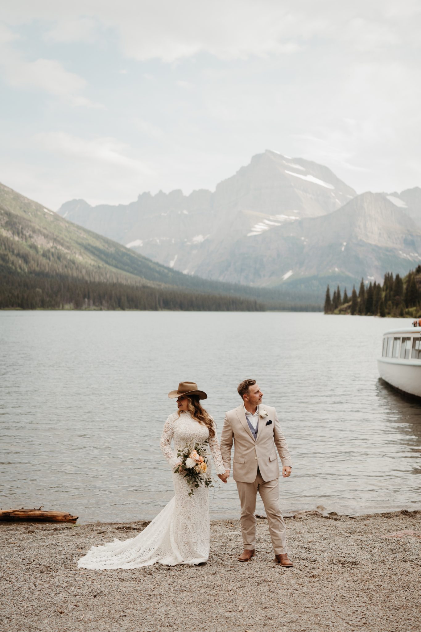 Montana Summer Elopement bride and groom holding hands with mountain views and a lake in the background