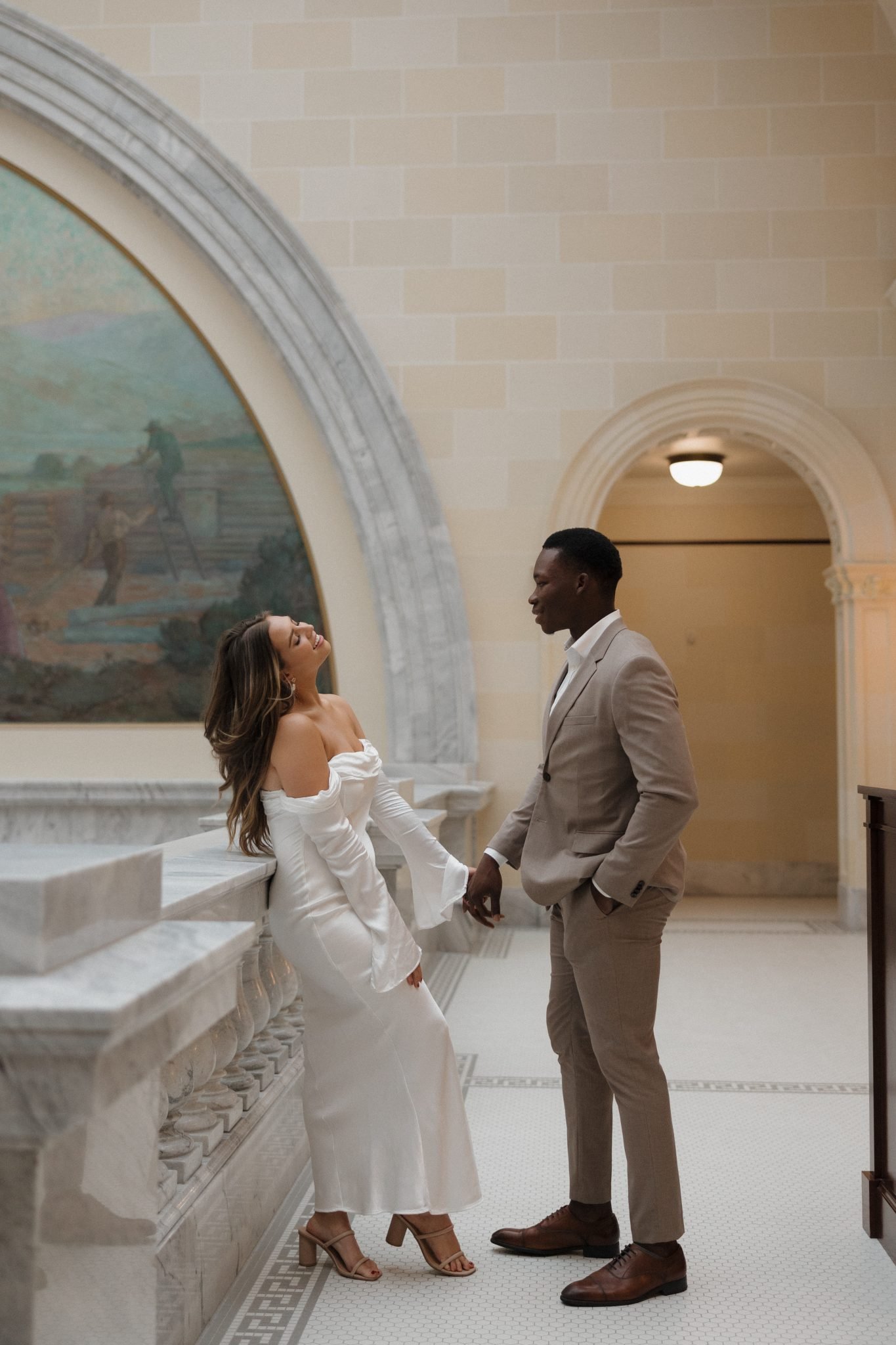 Bride leaning against the banister and groom is holding her hand for Utah wedding bridals