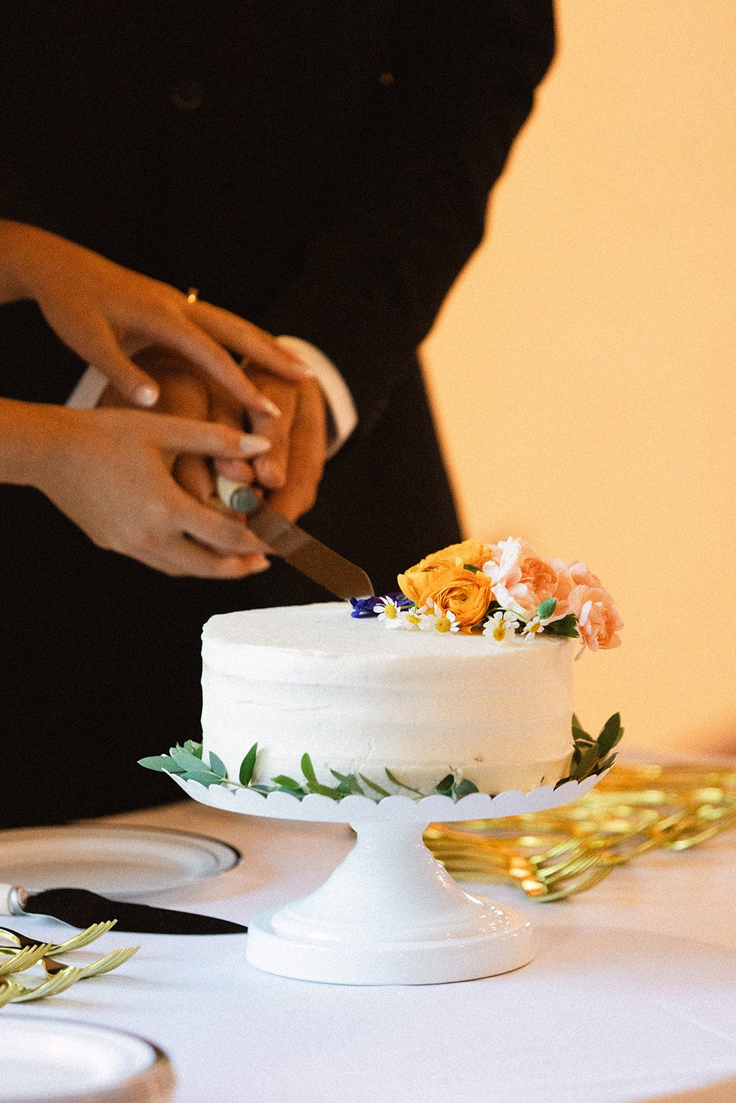 Highlands Ranch Summer Wedding couple cutting their one tiered wedding cake with florals on top