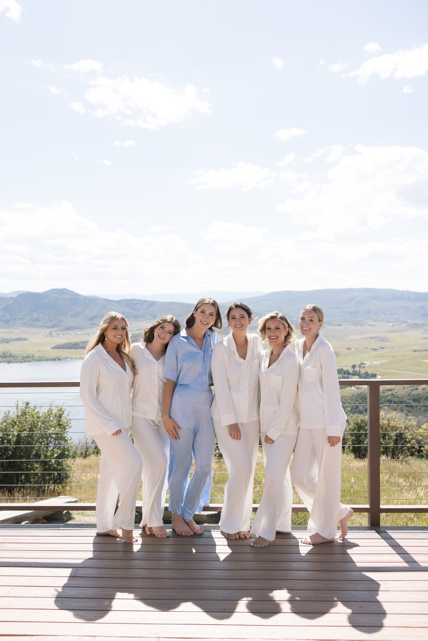 Matching bridesmaid PJ set while bridesmaids wear white and the bide wears blue with stunning mountain and lake views in the background for a Steamboat Springs Summer Wedding