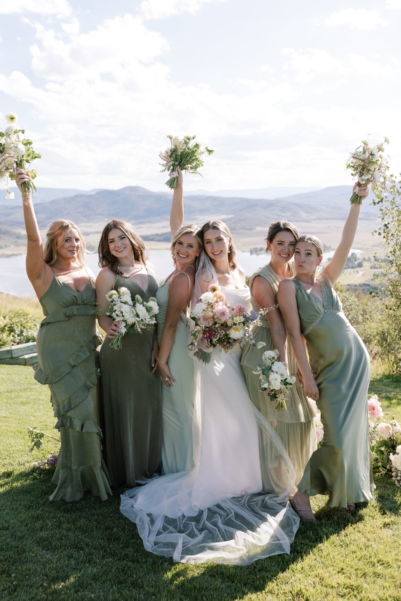Steamboat Springs Summer Wedding wearing different shades and textures of green bridesmaid dresses with a beautiful mountain and lakeside backdrop