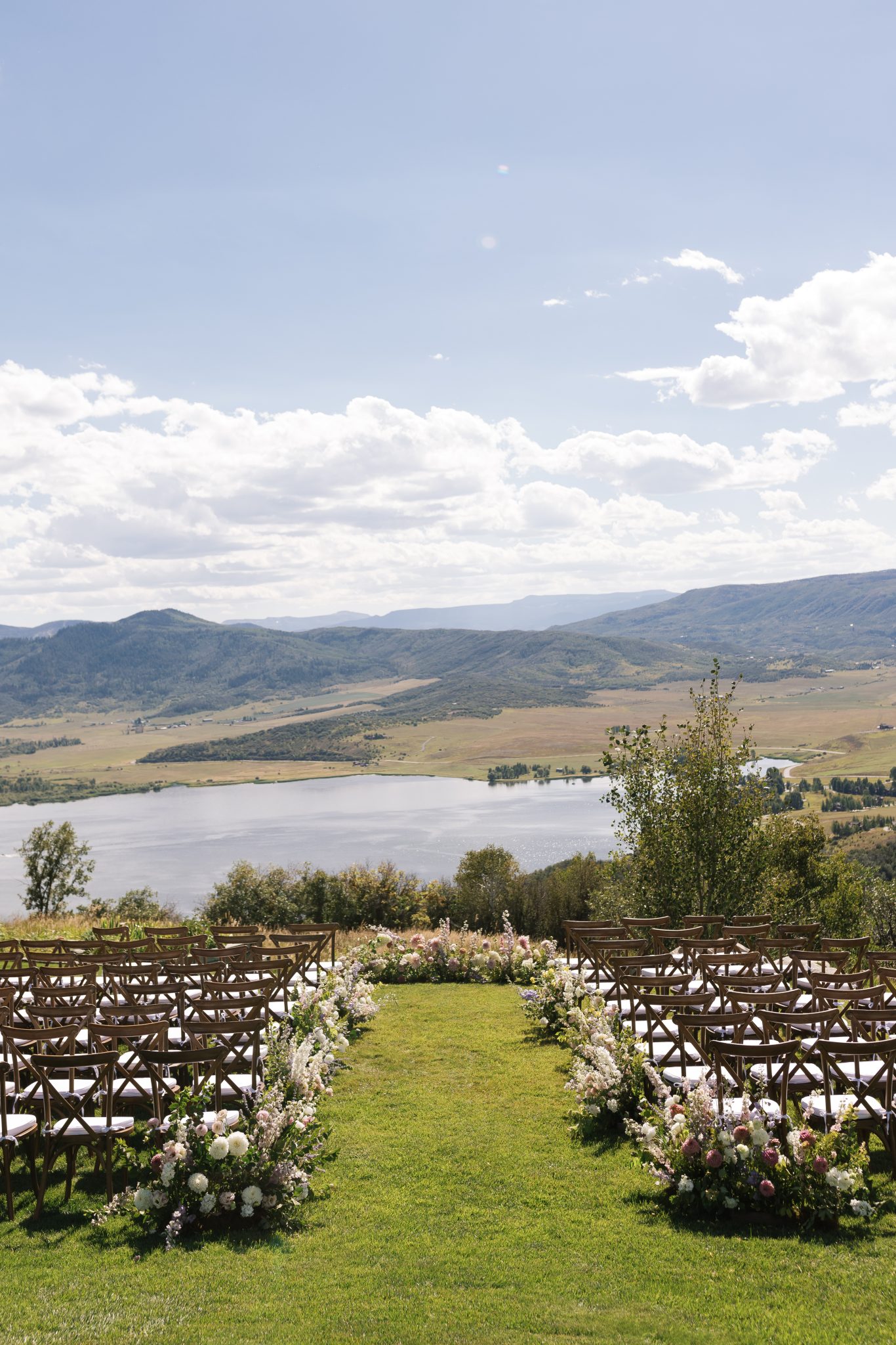 Steamboat Springs Summer Wedding ceremony views with mountain and lakeside views and floral arrangements aligning the aisle