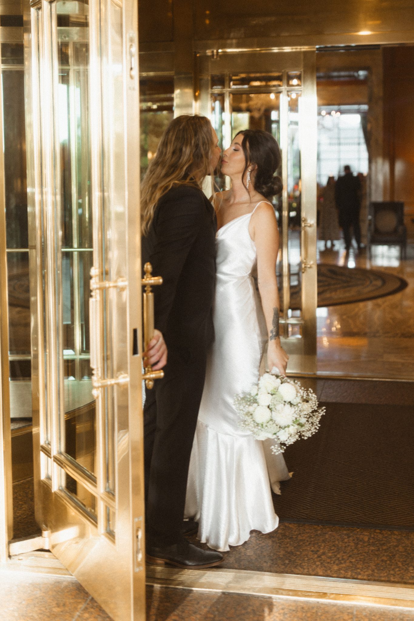 Salt Lake City Utah Wedding bride and groom kissing as the groom holds the door open and the bride's bouquet is hanging by her side