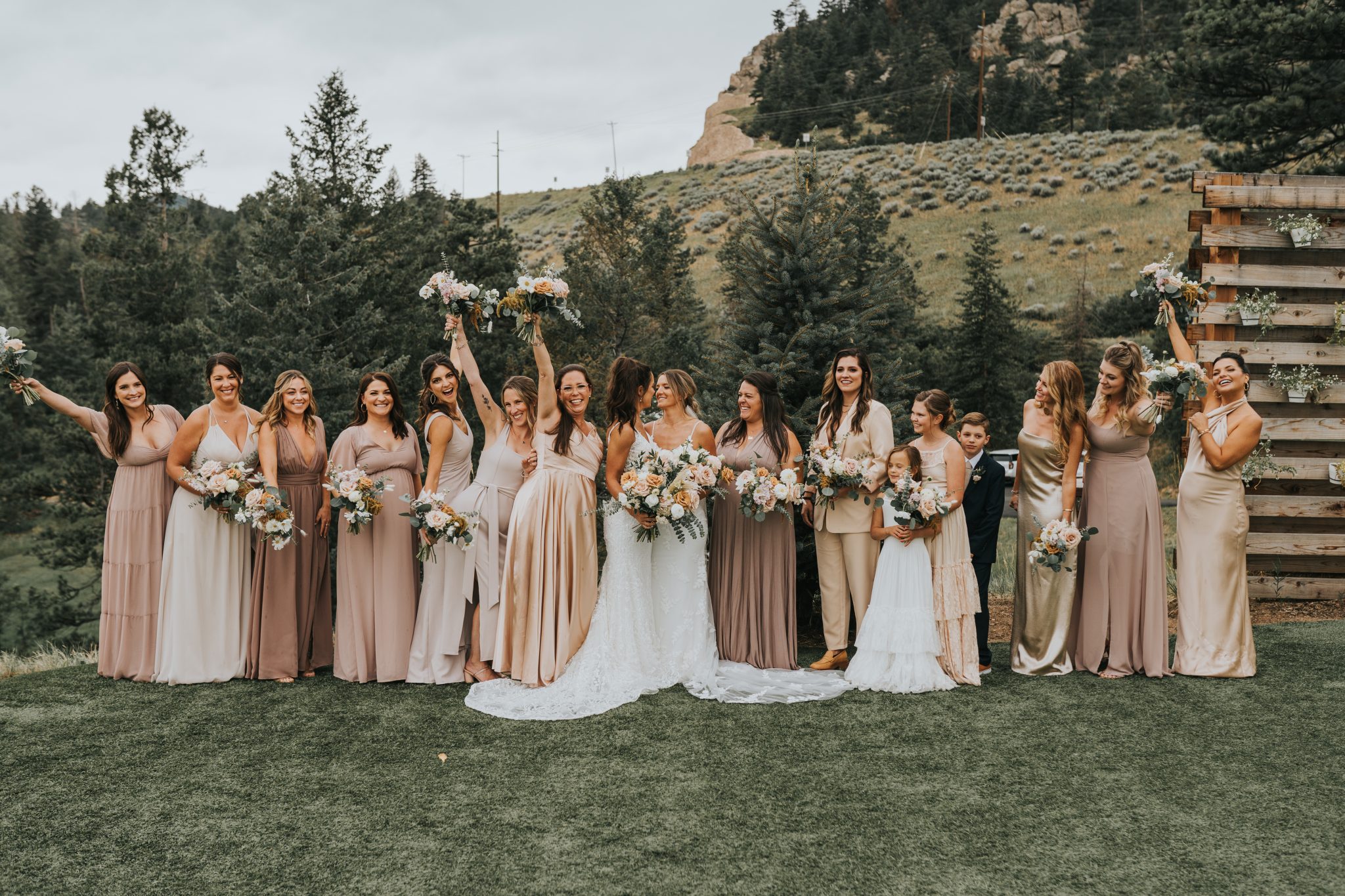 A group photo of bridesmaids in neutral-colored dresses, celebrating at a Colorado Winter Woodlands Wedding.