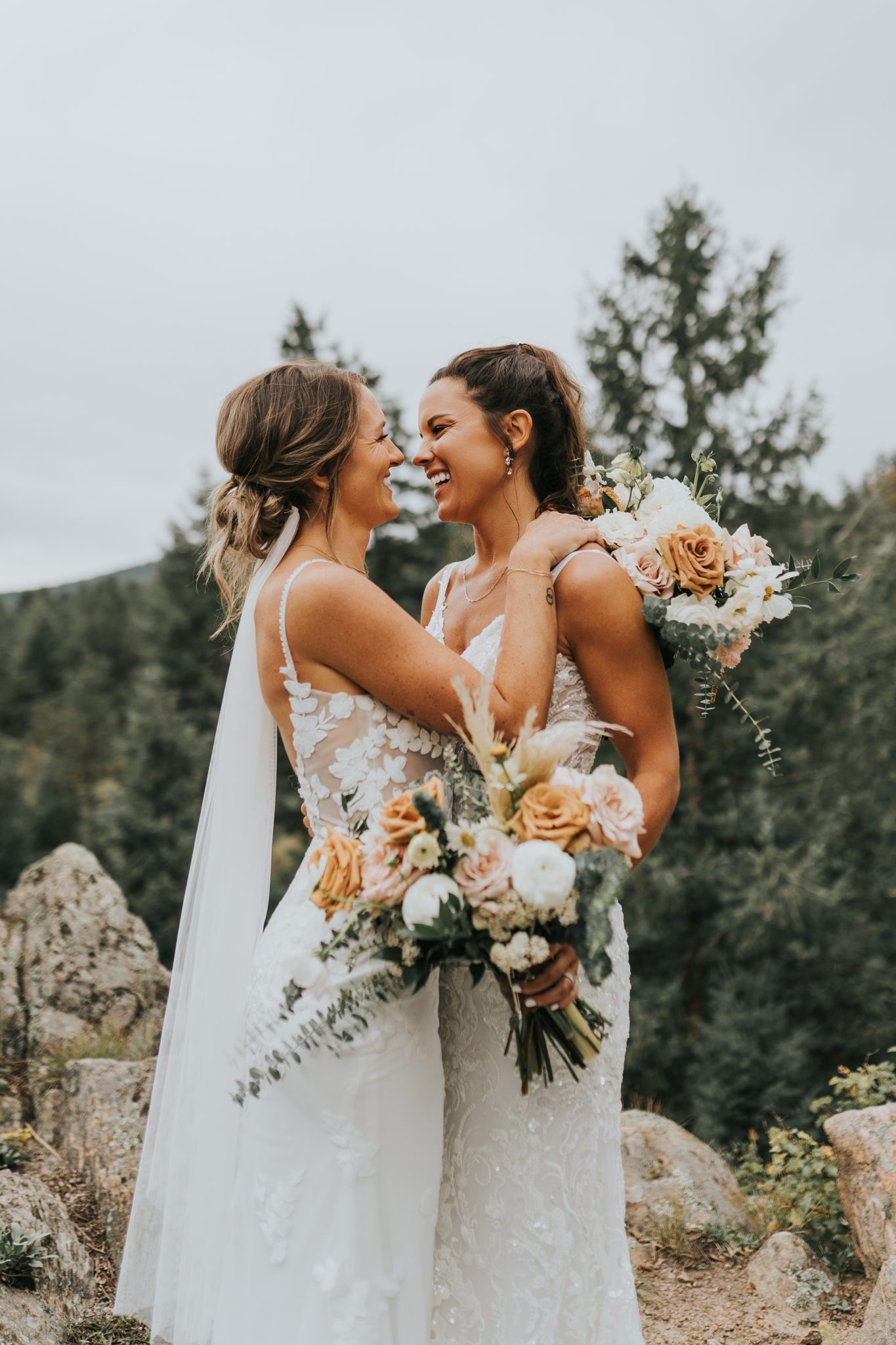 Two brides embracing each other in wedding gowns, showcasing the love at their Colorado Winter Woodlands Wedding.