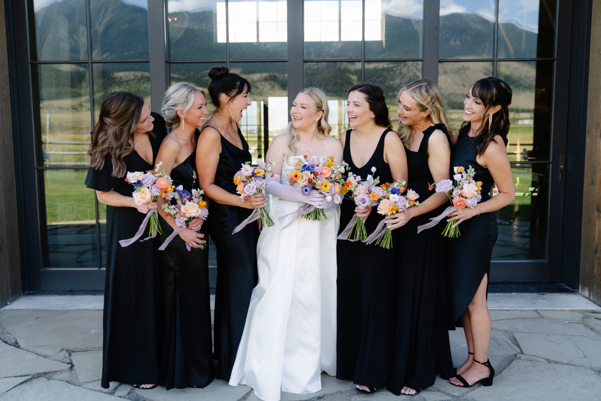 Copper Rose Ranch Wedding bridesmaids wearing black dresses and holding colorful floral bouquets