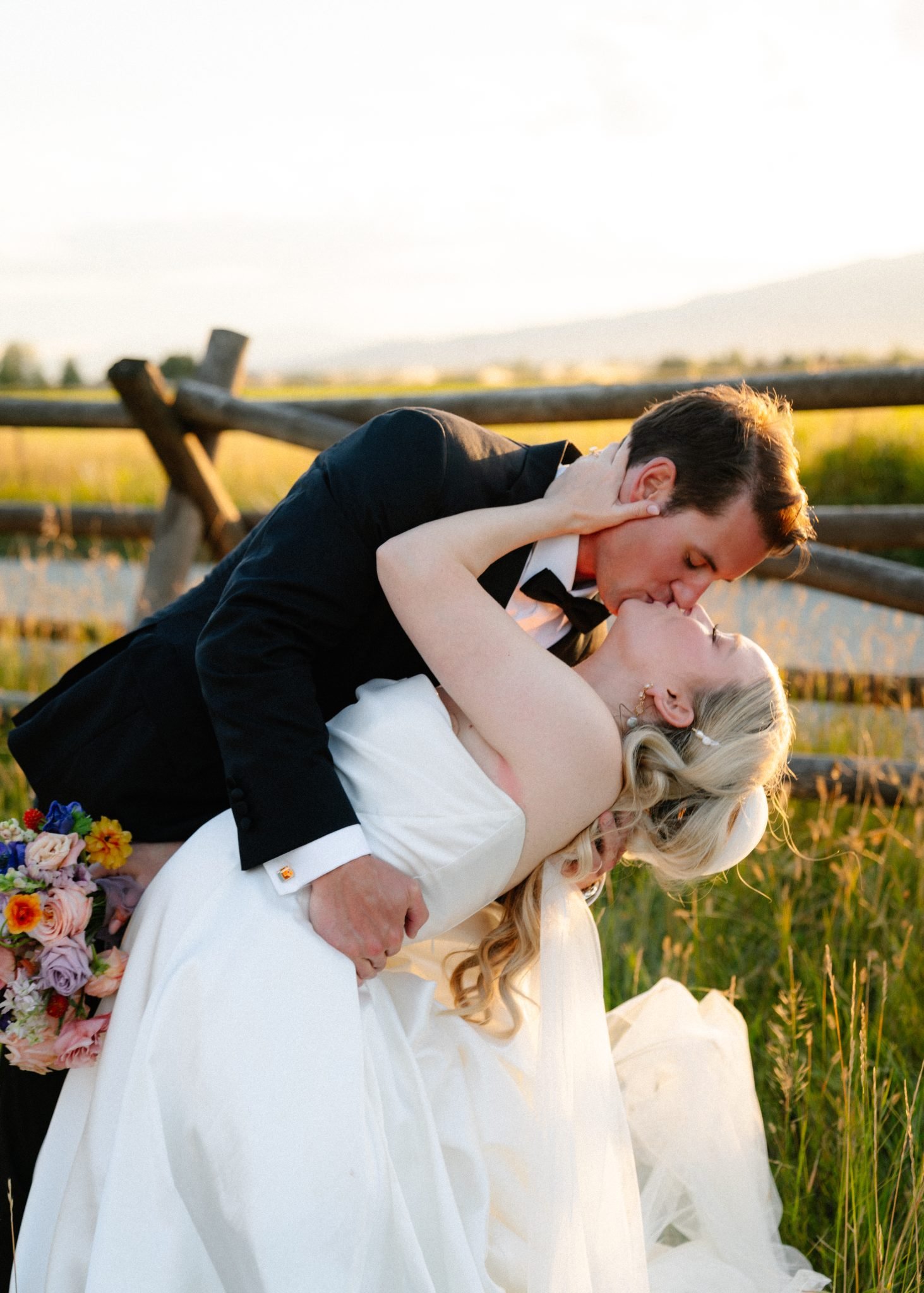 Copper Rose Ranch Wedding groom dips bride and kisses her as she puts her hand on the back of his neck