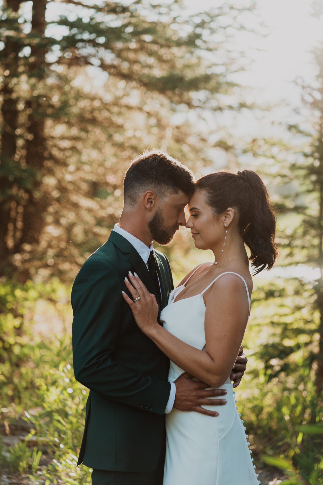 Grand Teton National Park Elopement bride and groom sharing an intimate moment in the woods amongst the trees and warm sunlight