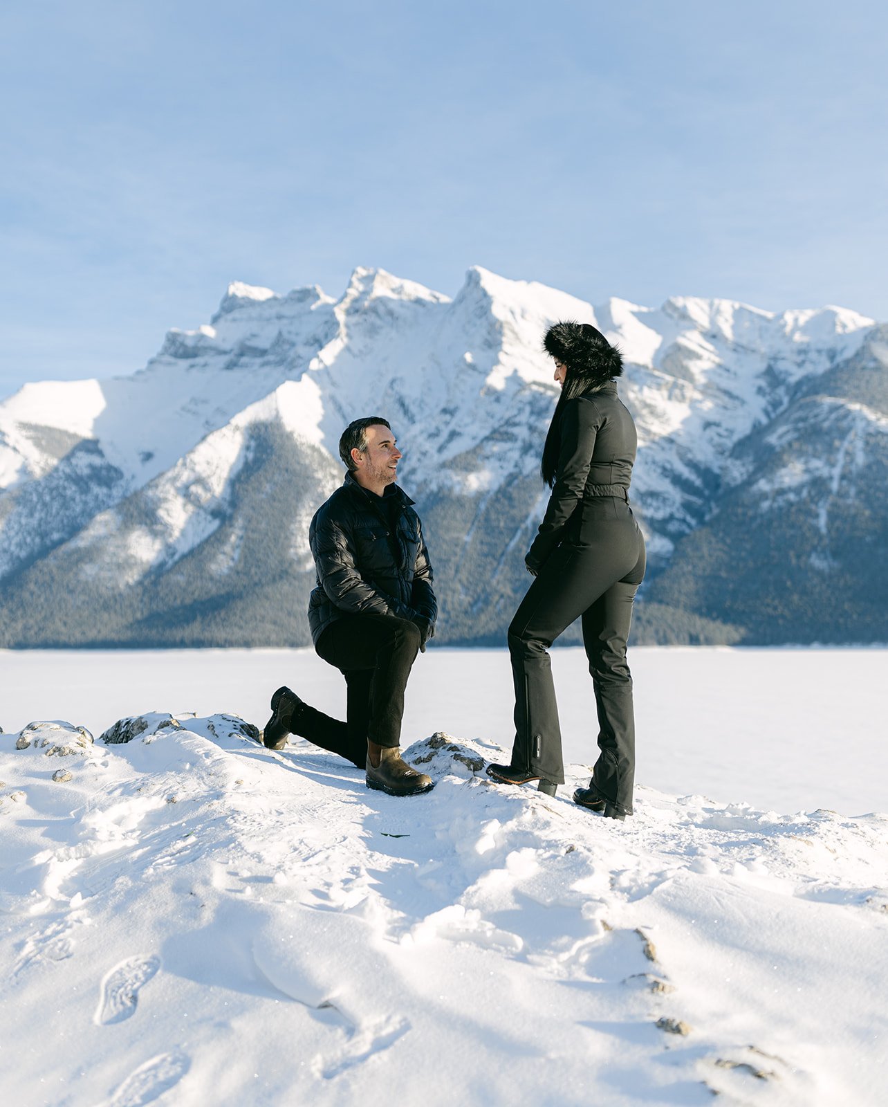 Alberta Wedding Proposal with snow capped mountains in the background as he is down on one knee asking her to marry him