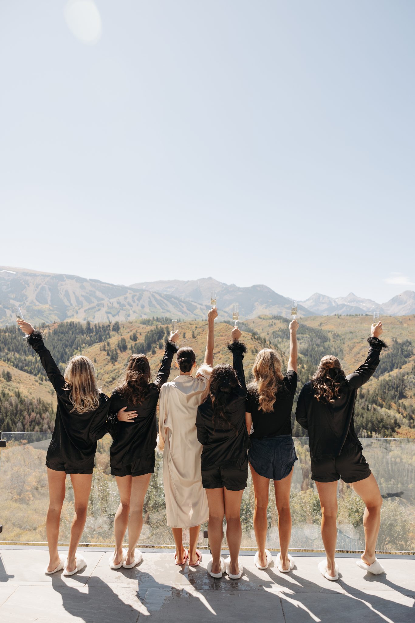 Snowmass Fall Wedding bridesmaids toasting to the start of the day as they get ready where the bridesmaids are wearing black matching pajama set