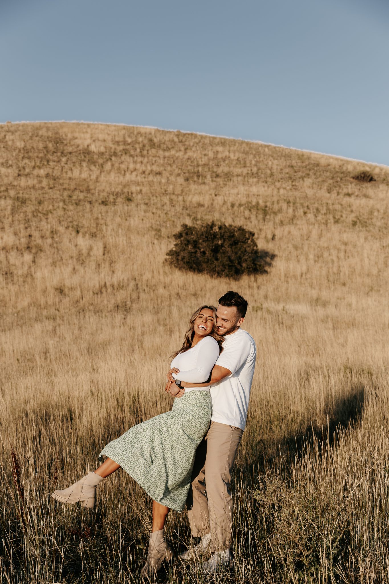 Utah Winter Engagement Session with his arms around her waist in a field with cute matching outfits