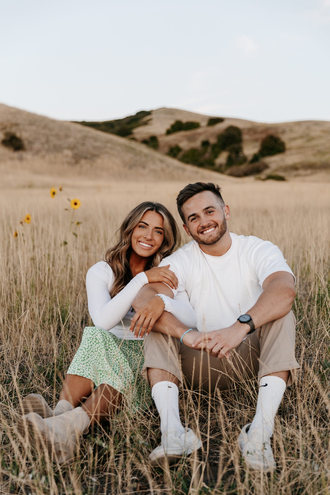 Utah Winter Engagement Session sitting in a field with dainty florals in the background