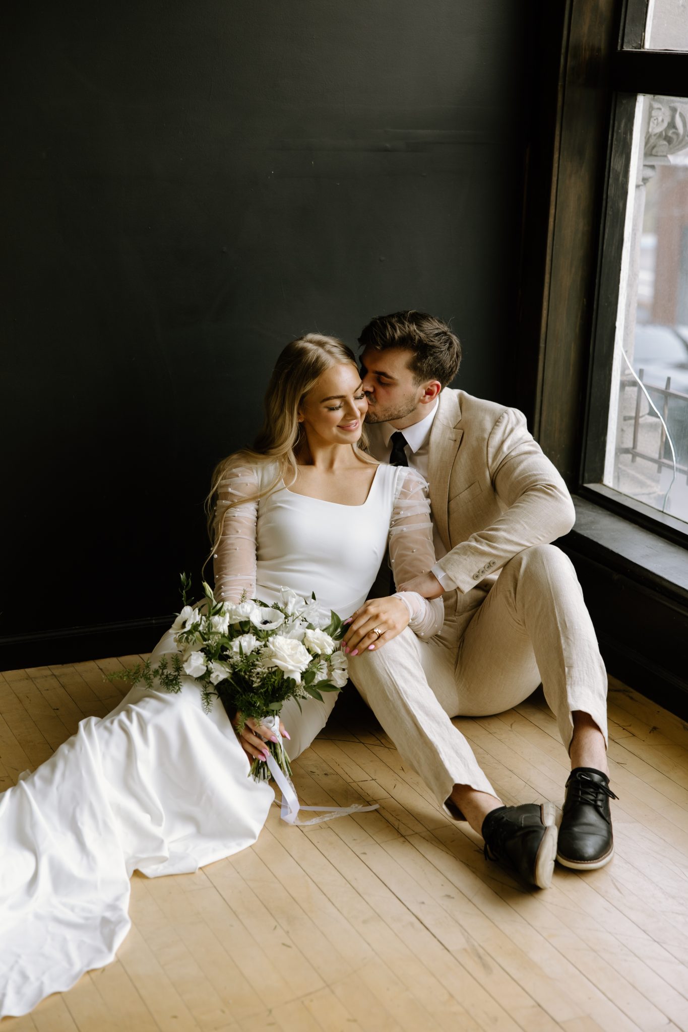 Winter Idaho Bridals at The Paris Studios groom kissing the bride's temple as they sit on the ground