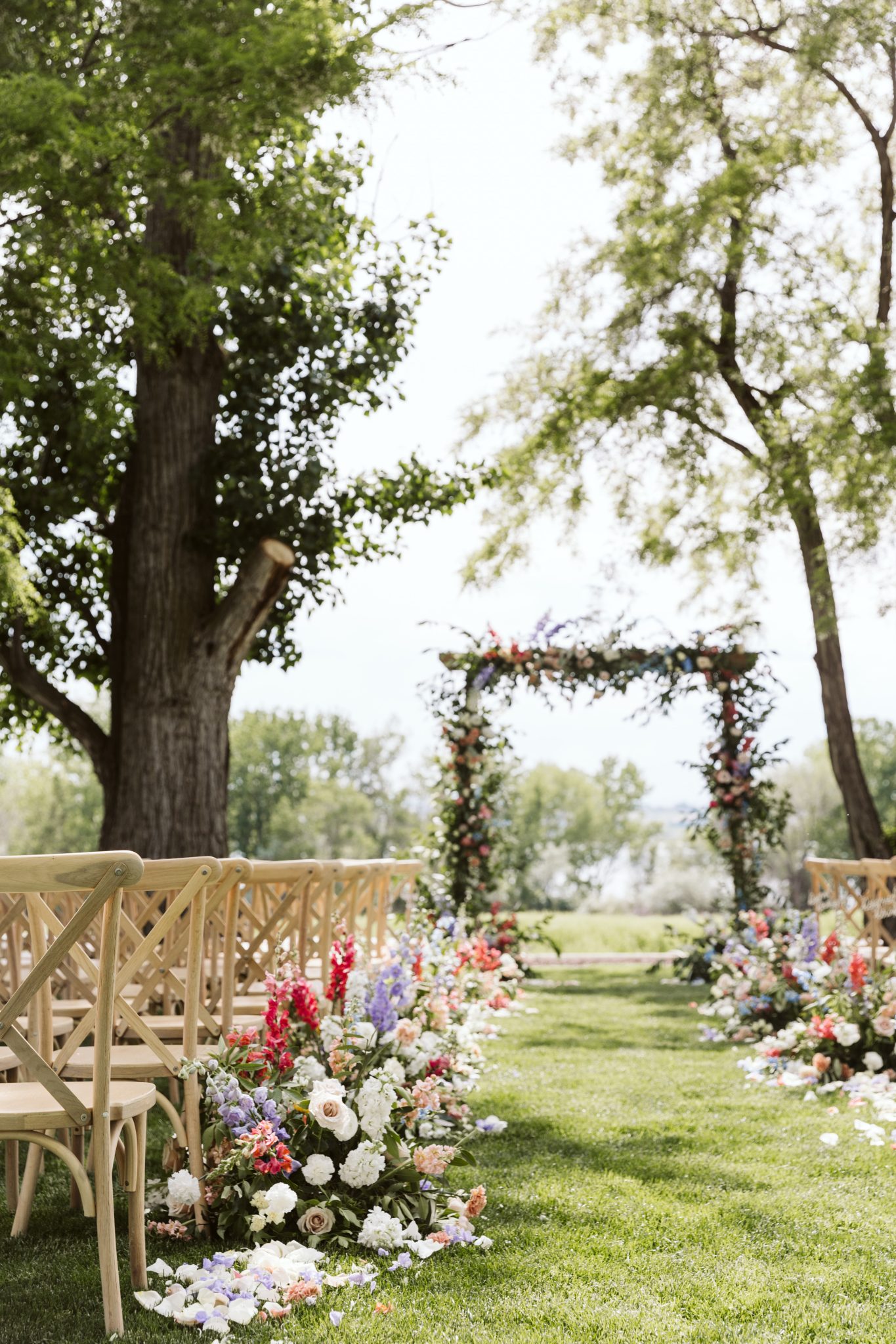 Outdoor wedding ceremony setup with colorful floral arch at Deer Flat Ranch Spring Wedding.