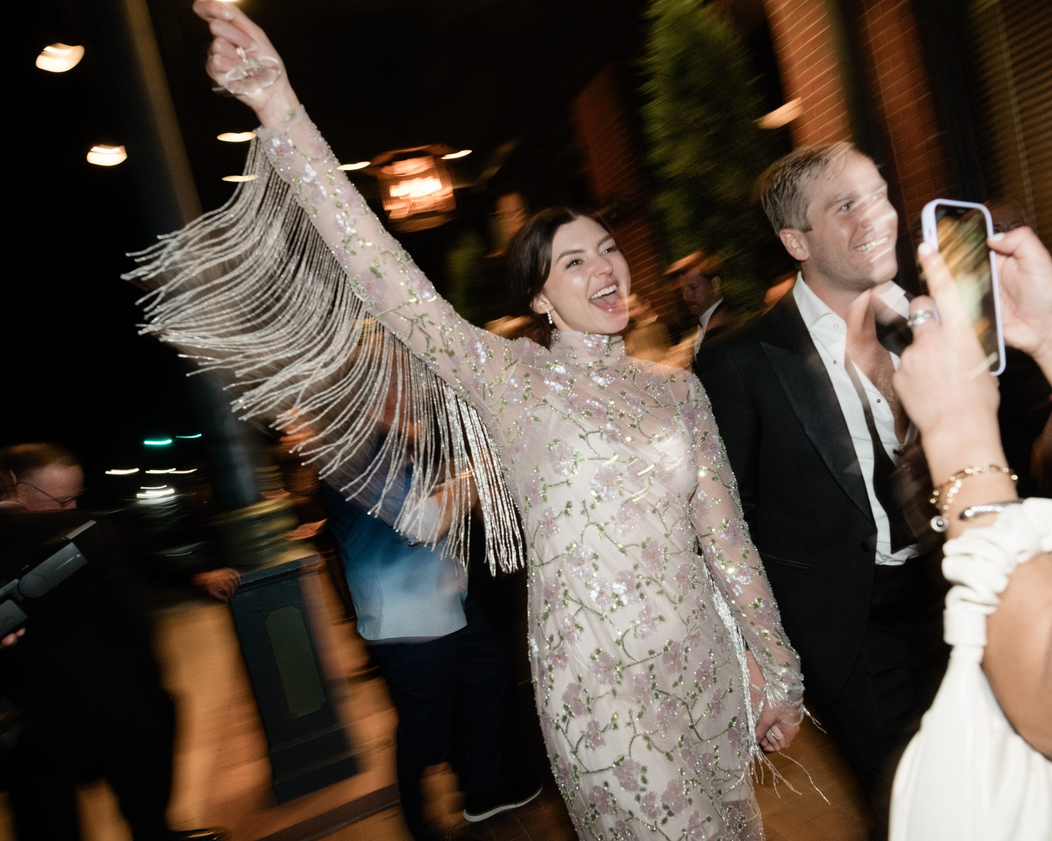 Bride in a glamorous fringed dress celebrating with groom at Hotel Jerome wedding.