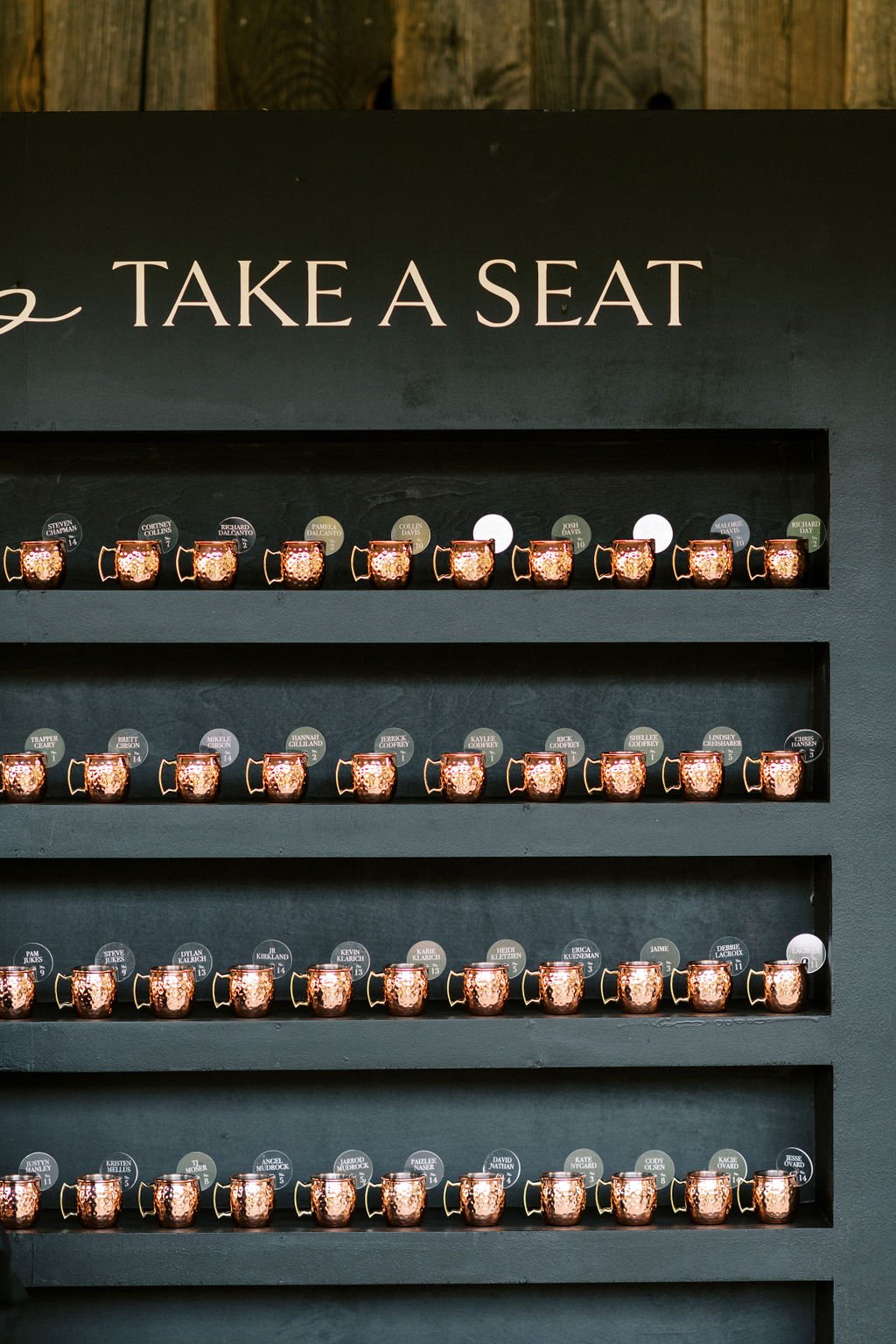 A creative seating chart display with mini copper mugs for a Peoa Spring Wedding.