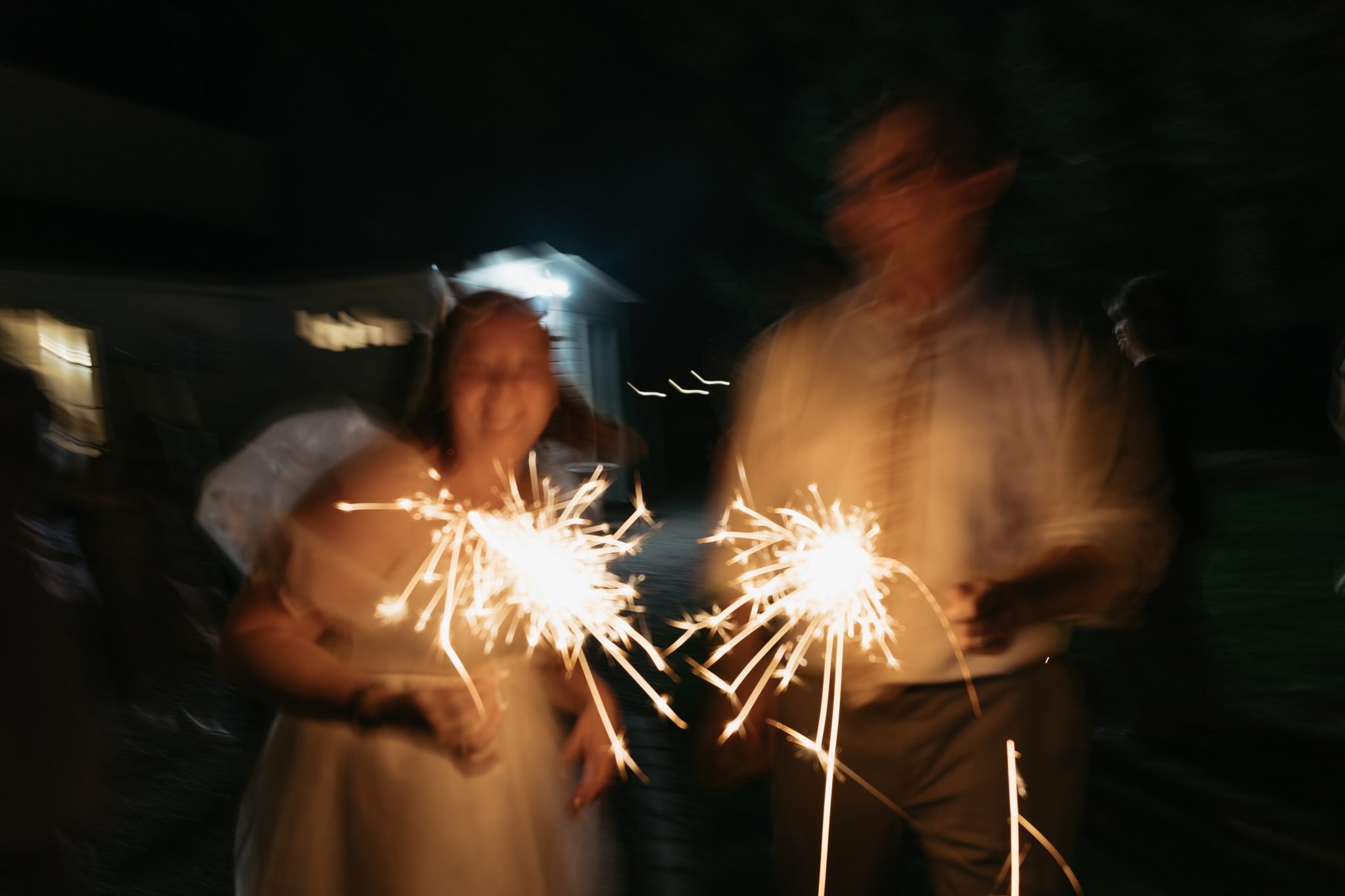 Bride and groom holding sparklers during their summer wedding at The Vintage Rose Wedding Venue.