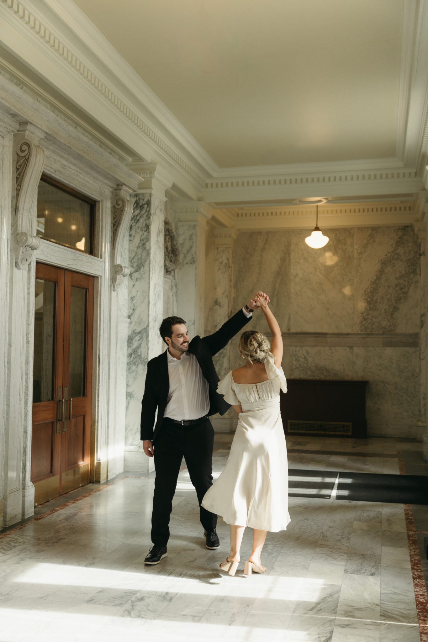A couple dancing in an elegant marble hallway, capturing their wedding engagement session in Idaho.
