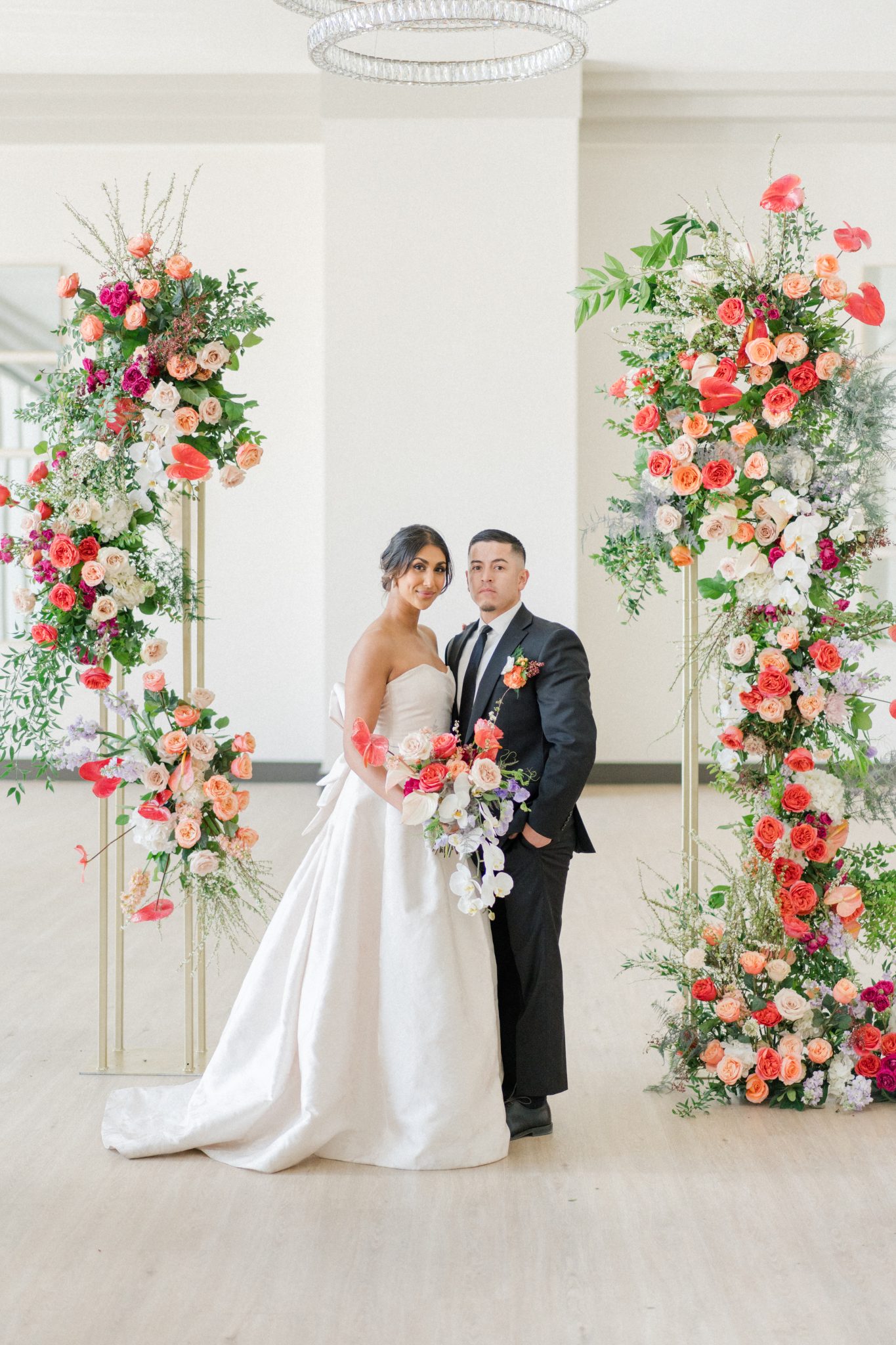 Bride and groom standing amidst lush floral pillars at their Downtown Colorado wedding.