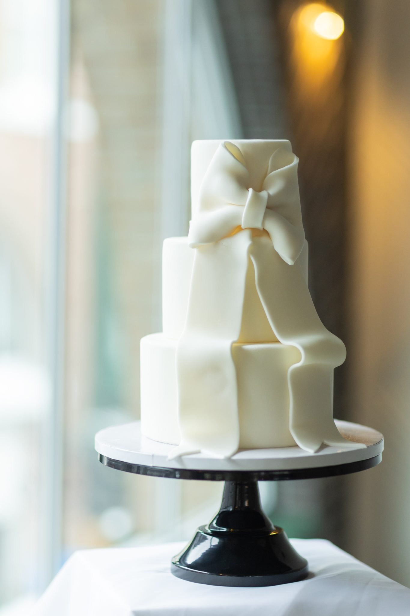 Close-up of a white wedding cake with a large bow at a Chilliwack wedding inspiration event.