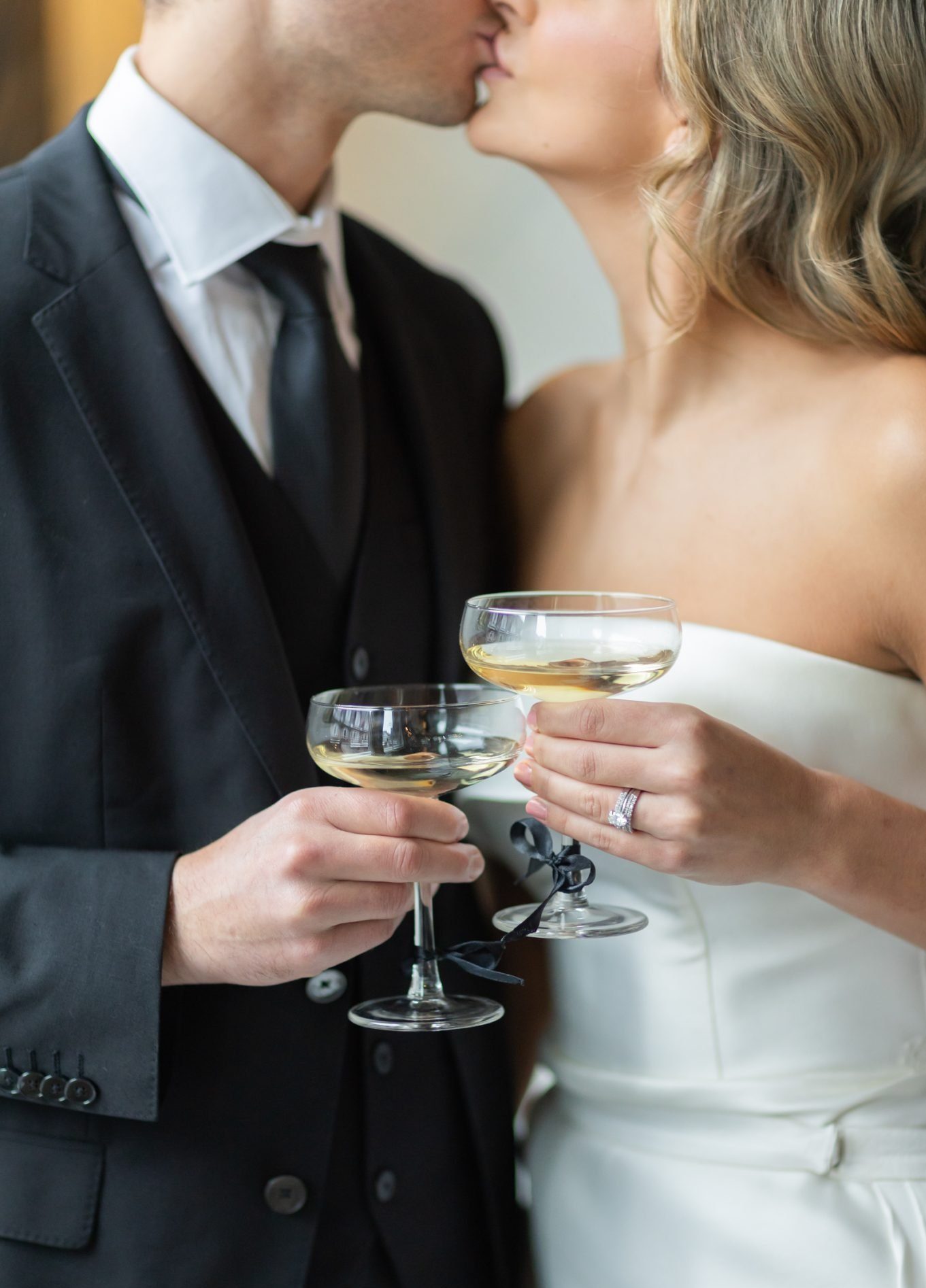 Photo of a bride and groom kissing while holding champagne glasses at a Chilliwack wedding inspiration event.