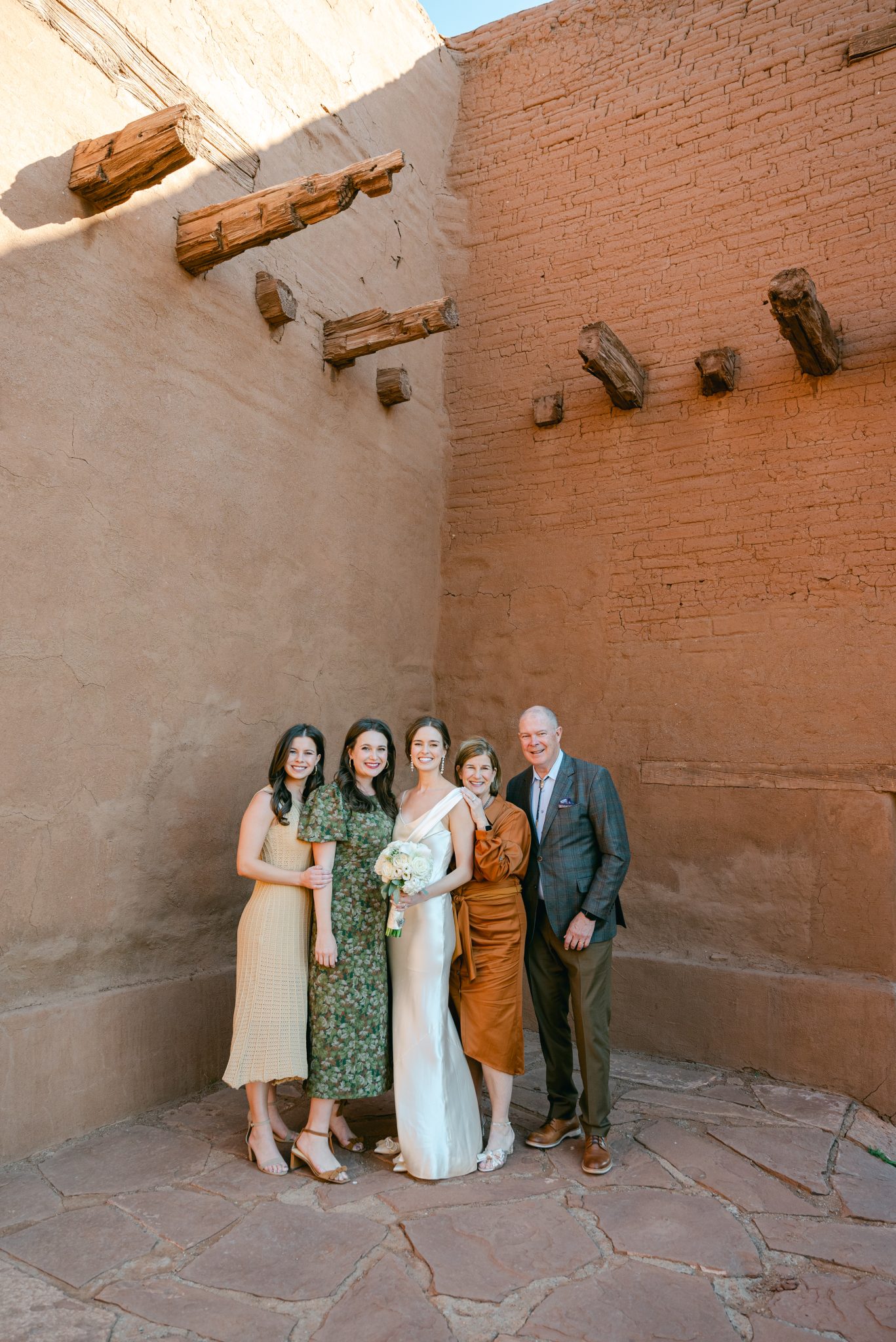 Family portrait against a terracotta, clay wall in Santa Fe during an intimate elopement.