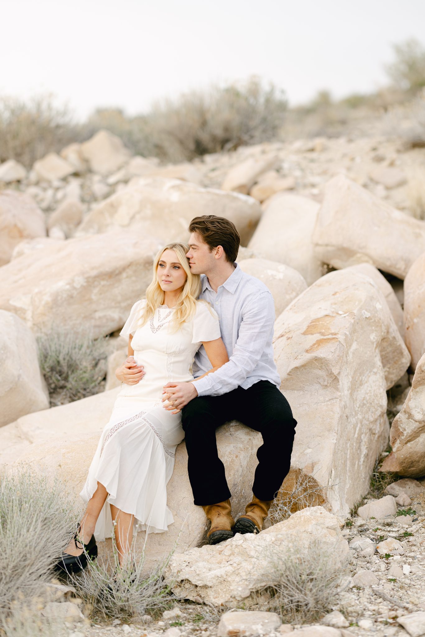 Couple sitting on rocks, sharing a quiet moment during their Utah pink lake engagement photos.