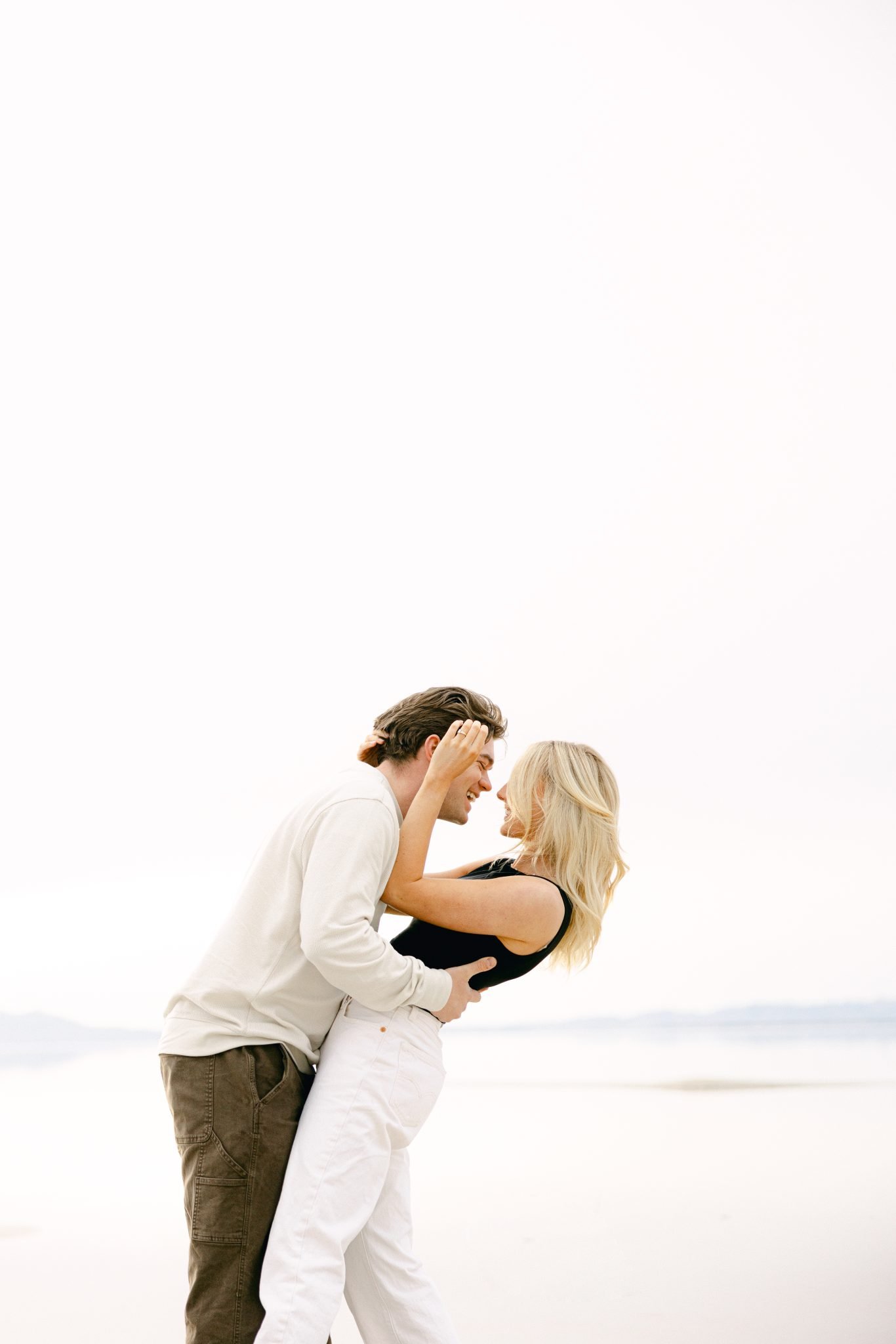 A couple embracing and laughing at Utah's pink lake engagement session.