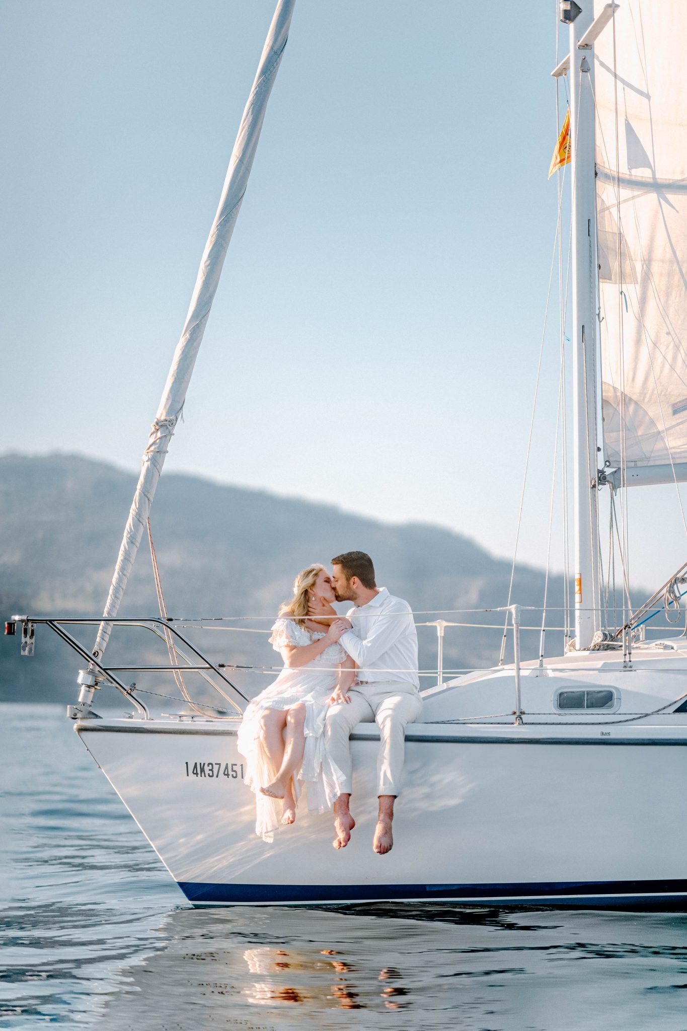 Kelowna summer engagement couple kissing on sailboat