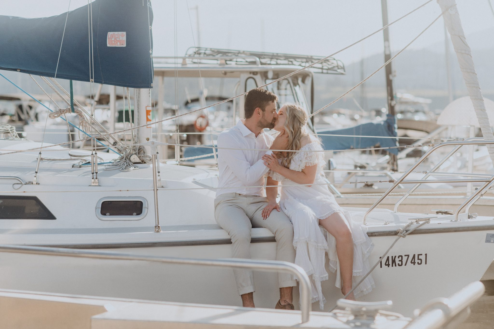 Romantic couple kissing on a sailboat at Kelowna summer engagement