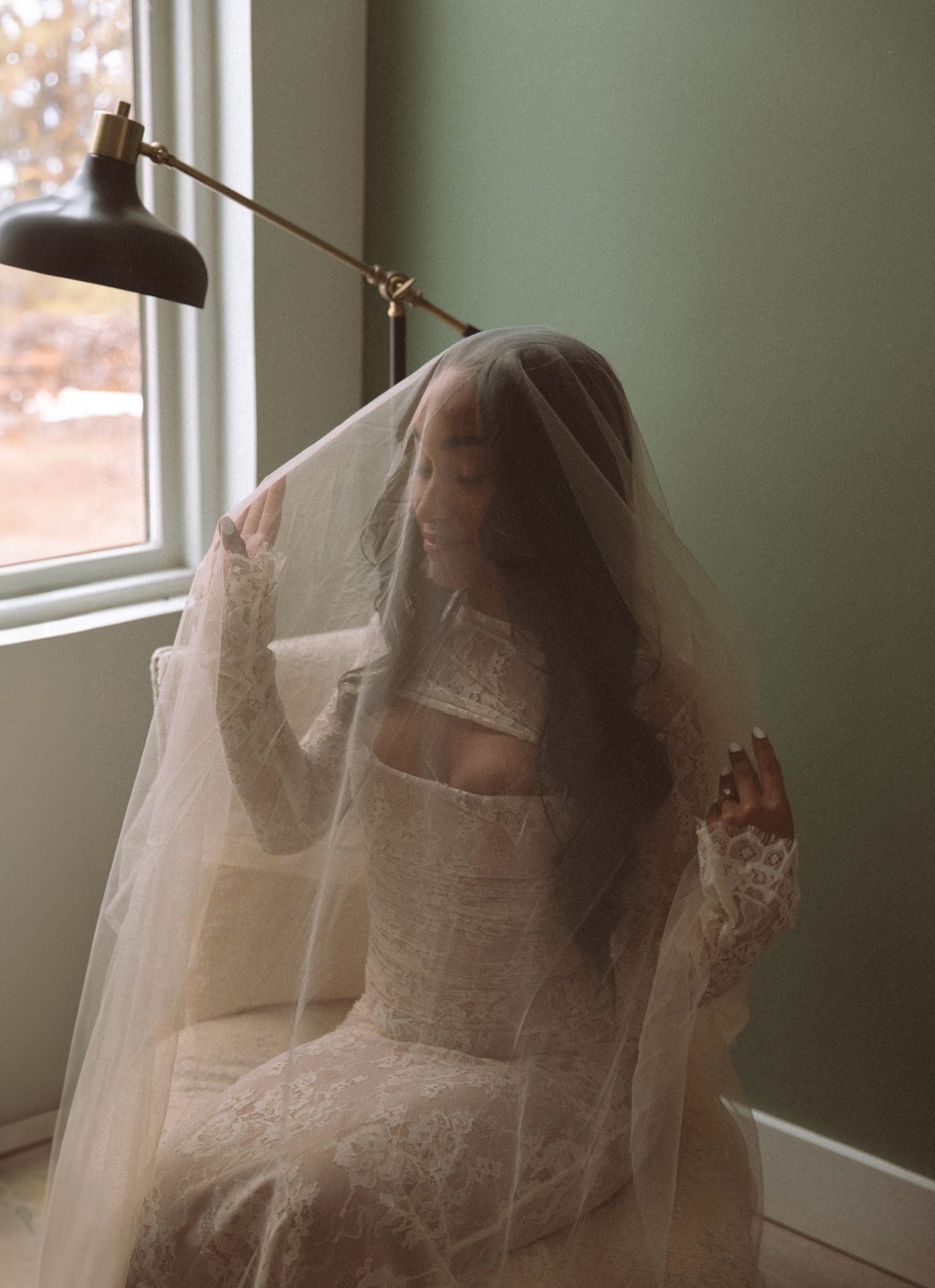 A bride sits gracefully under her veil, illuminated by soft natural light in a simple Colorado mountain elopement.