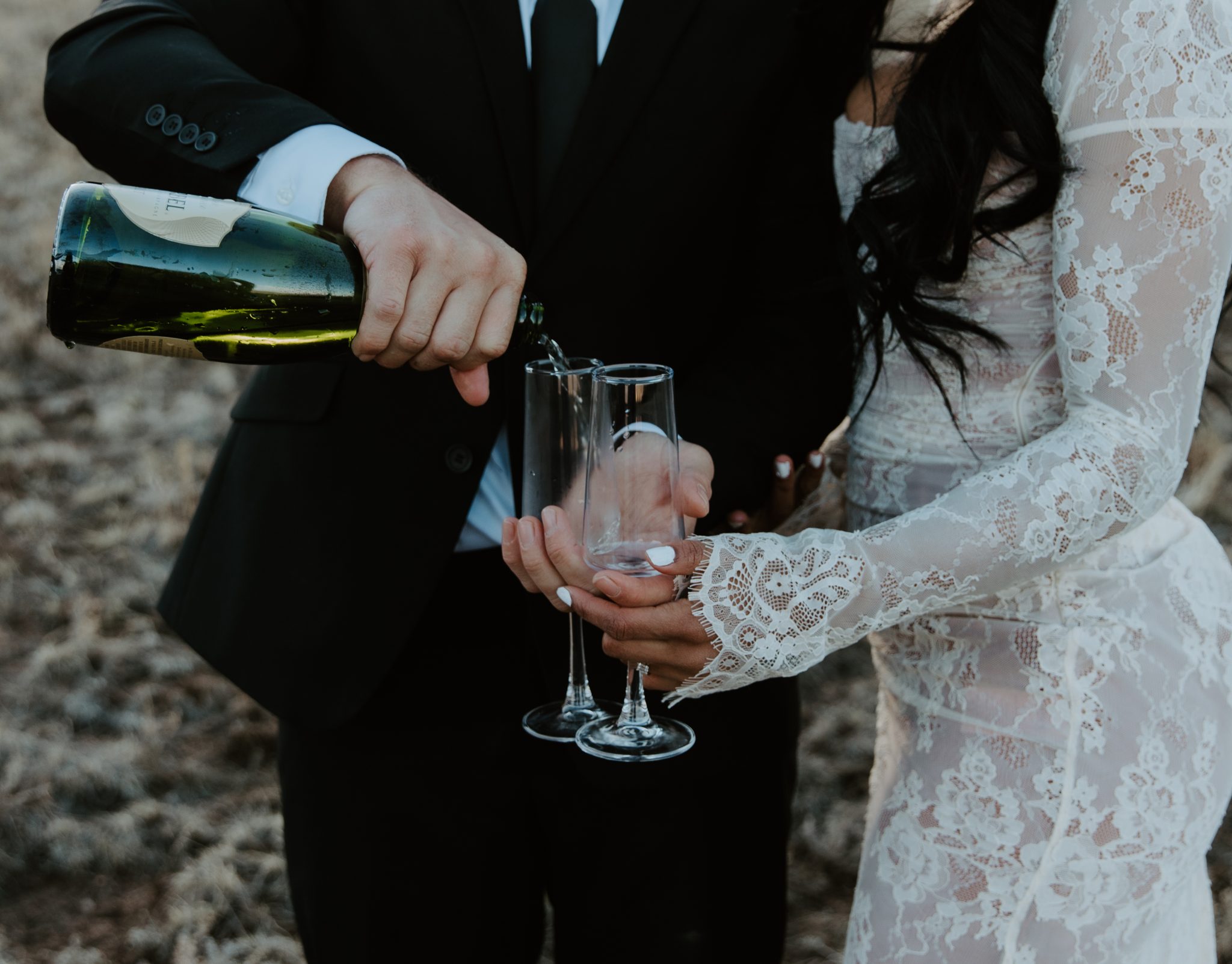 The bride and groom celebrate their elopement by pouring champagne in a serene Colorado mountain setting.