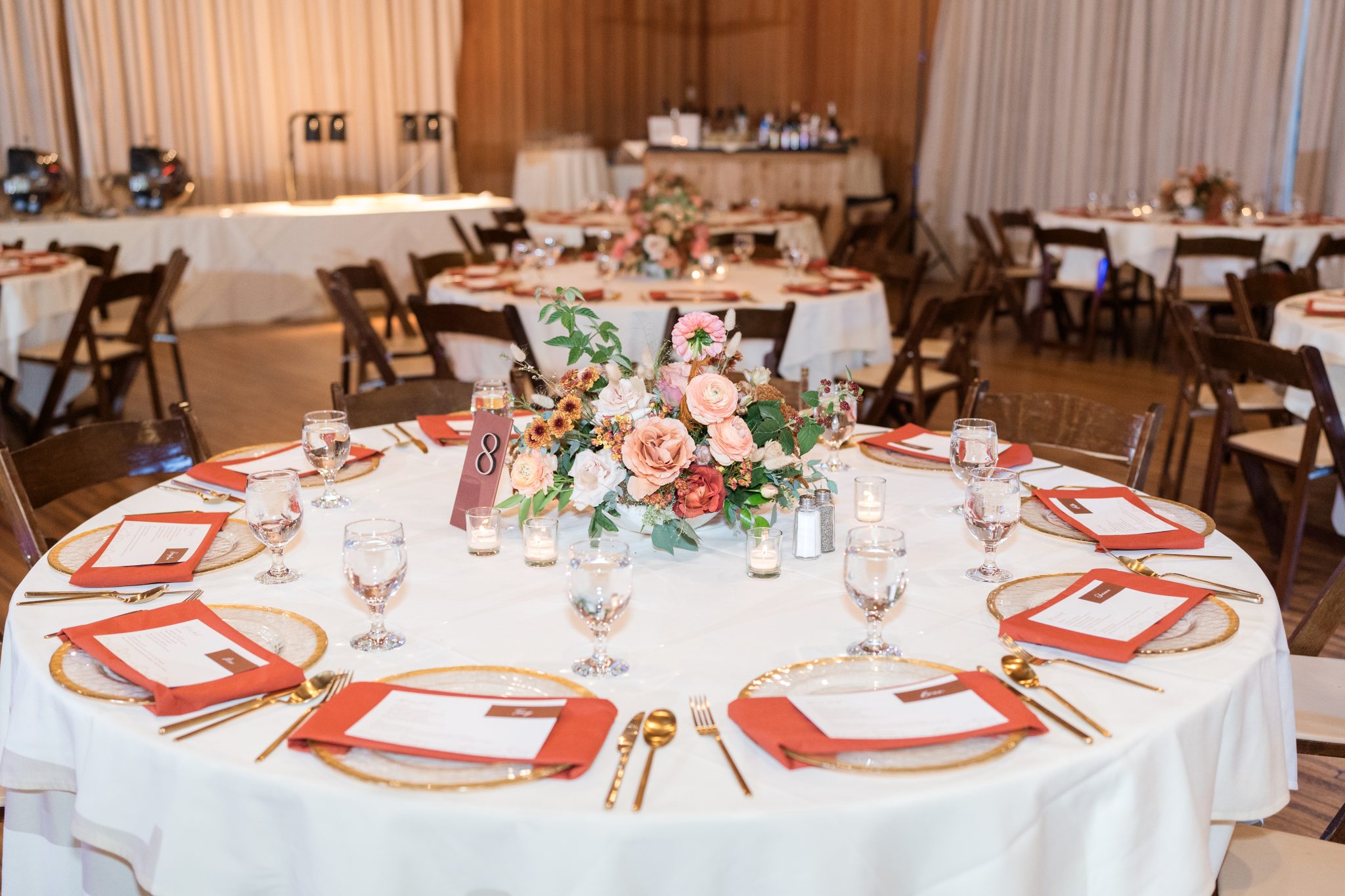 Elegant table setting with fall floral centerpiece and orange accents at a Utah fall wedding reception.