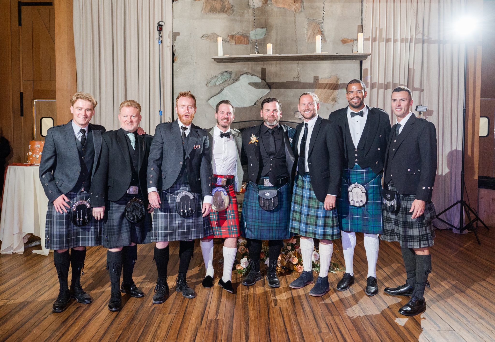 Groom and groomsmen dressed in kilts, standing together at a rustic Utah fall wedding celebration.