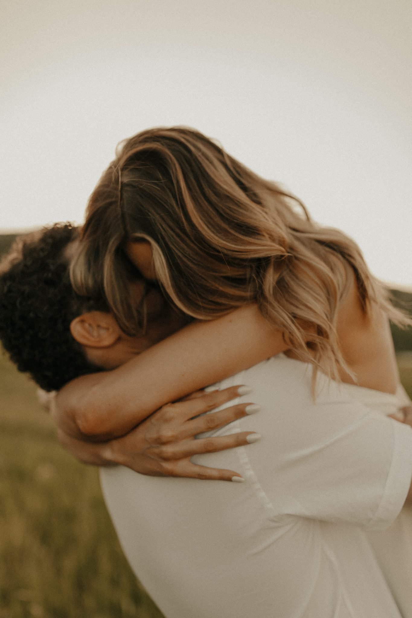 Couple sharing a romantic hug at sunset during their Colorado summer engagement session in the fields.