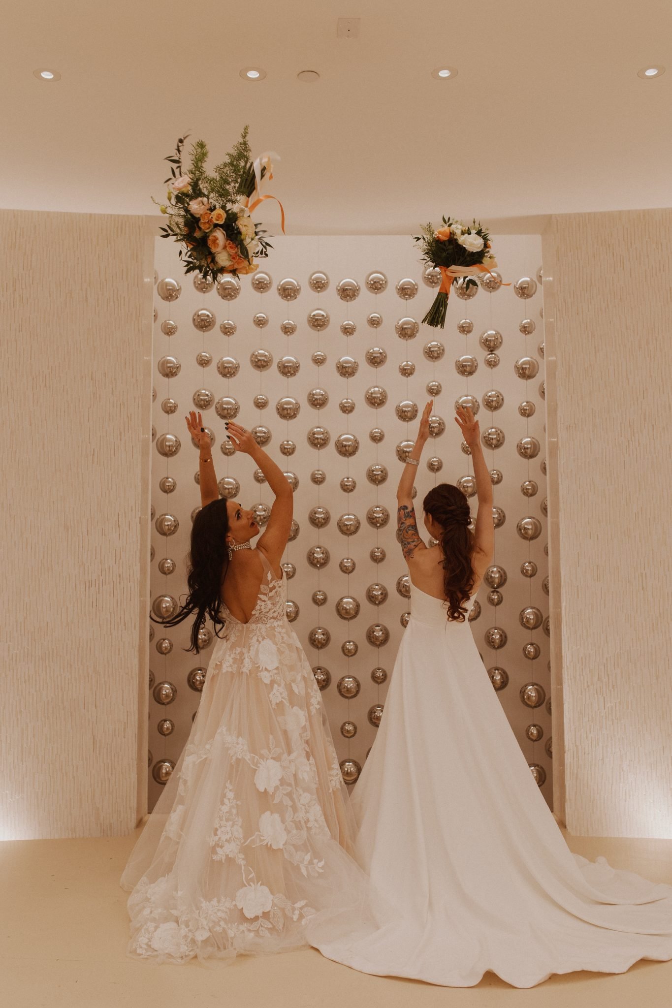 Brides joyfully tossing bouquets during a fun moment at their Albuquerque wedding.